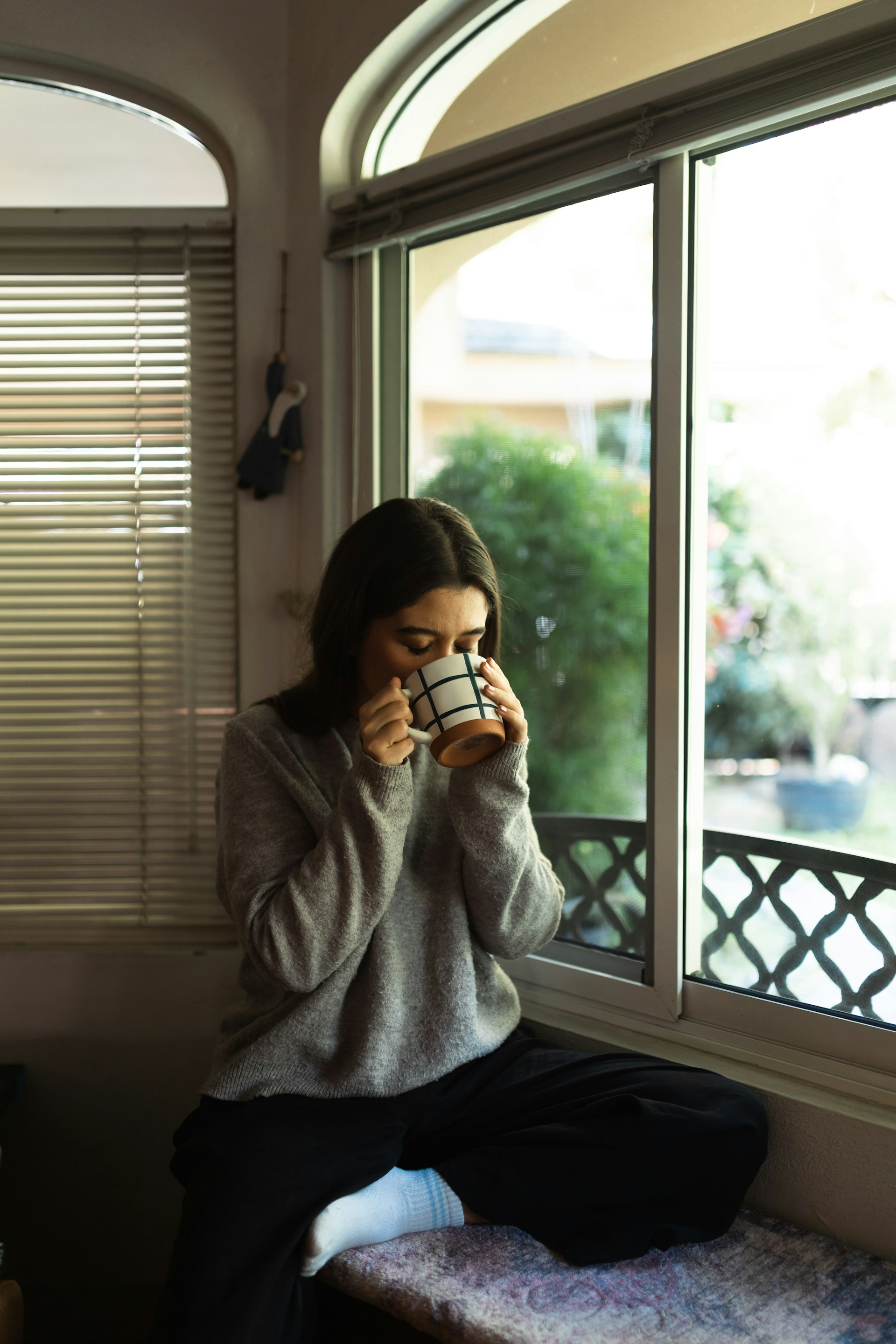 Woman drinking coffee by the window