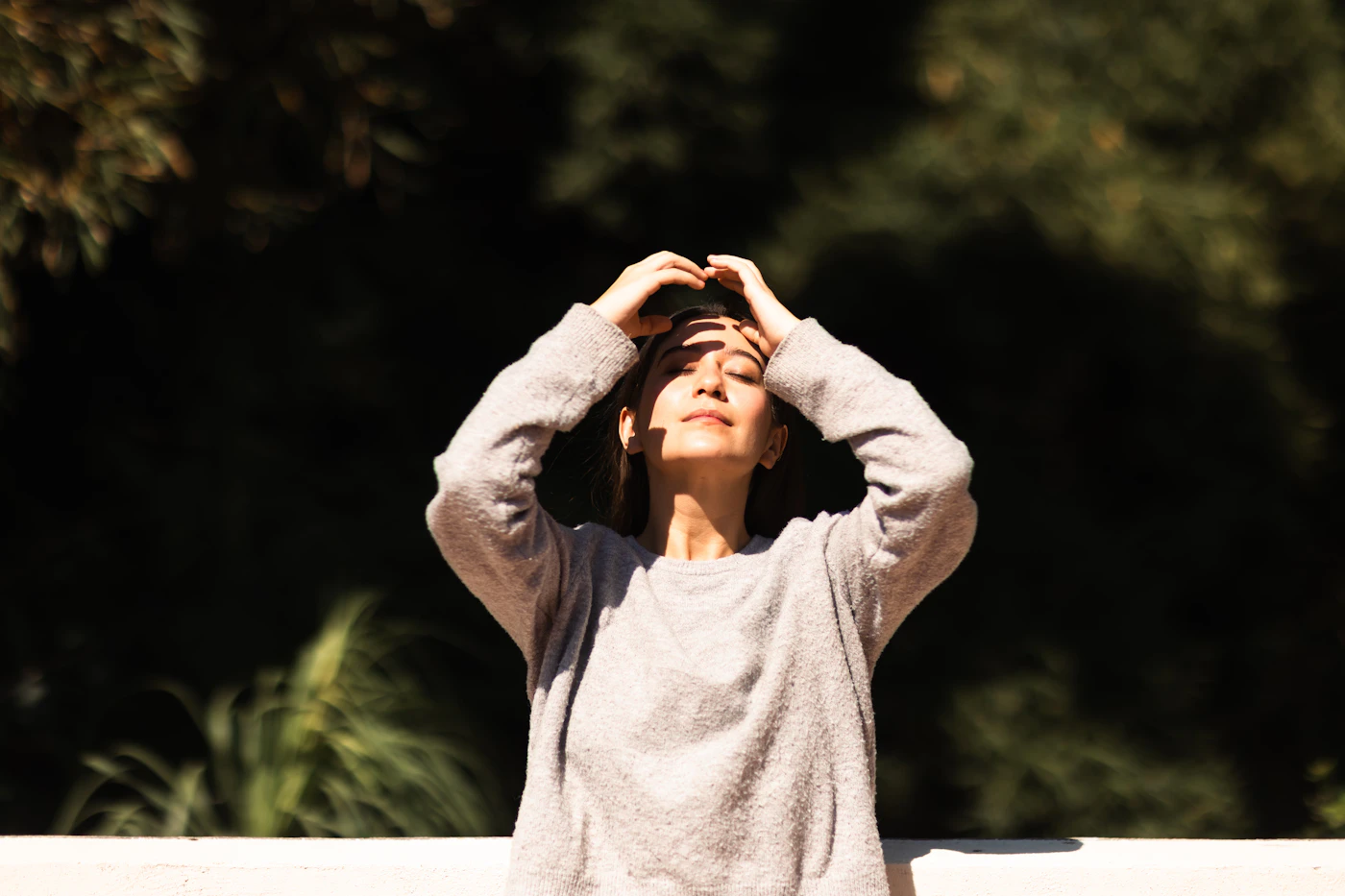 Frau mit geschlossenen Augen im Sonnenlicht als Symbol für einen ruhigen Moment während eines Cravings