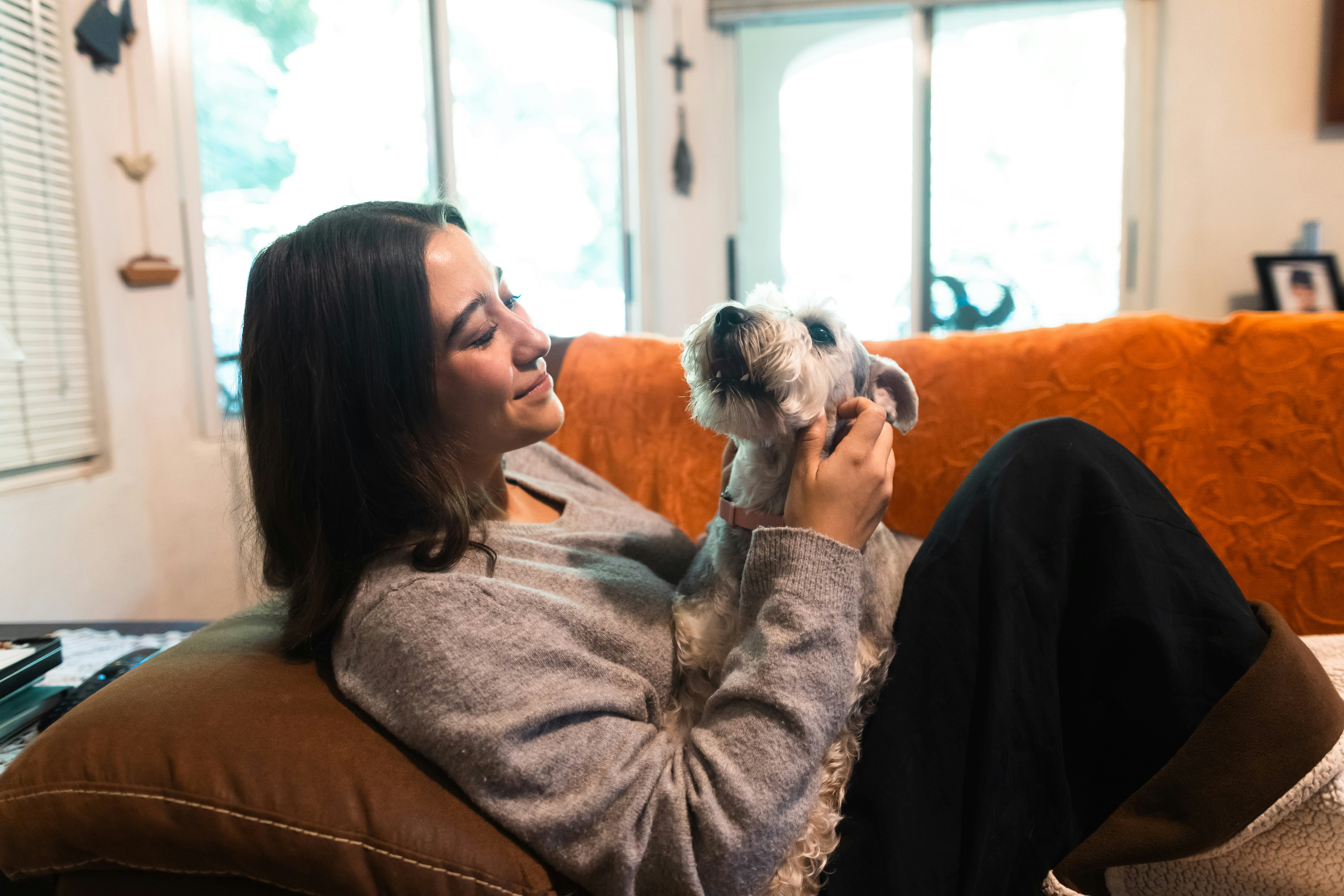 Young woman cuddling with her small dog on the couch.