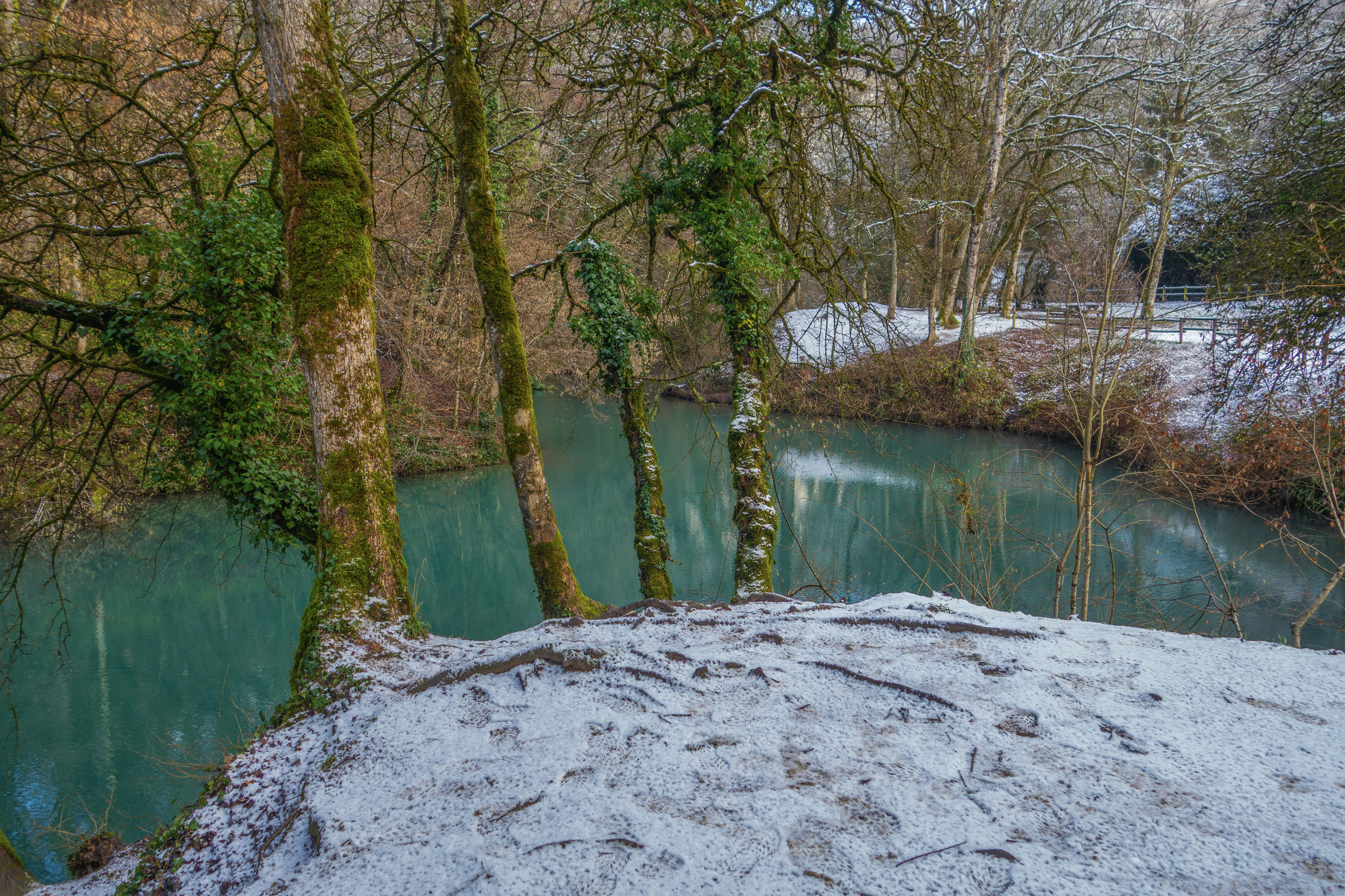 Snow-covered bank beside a tranquil blue river
