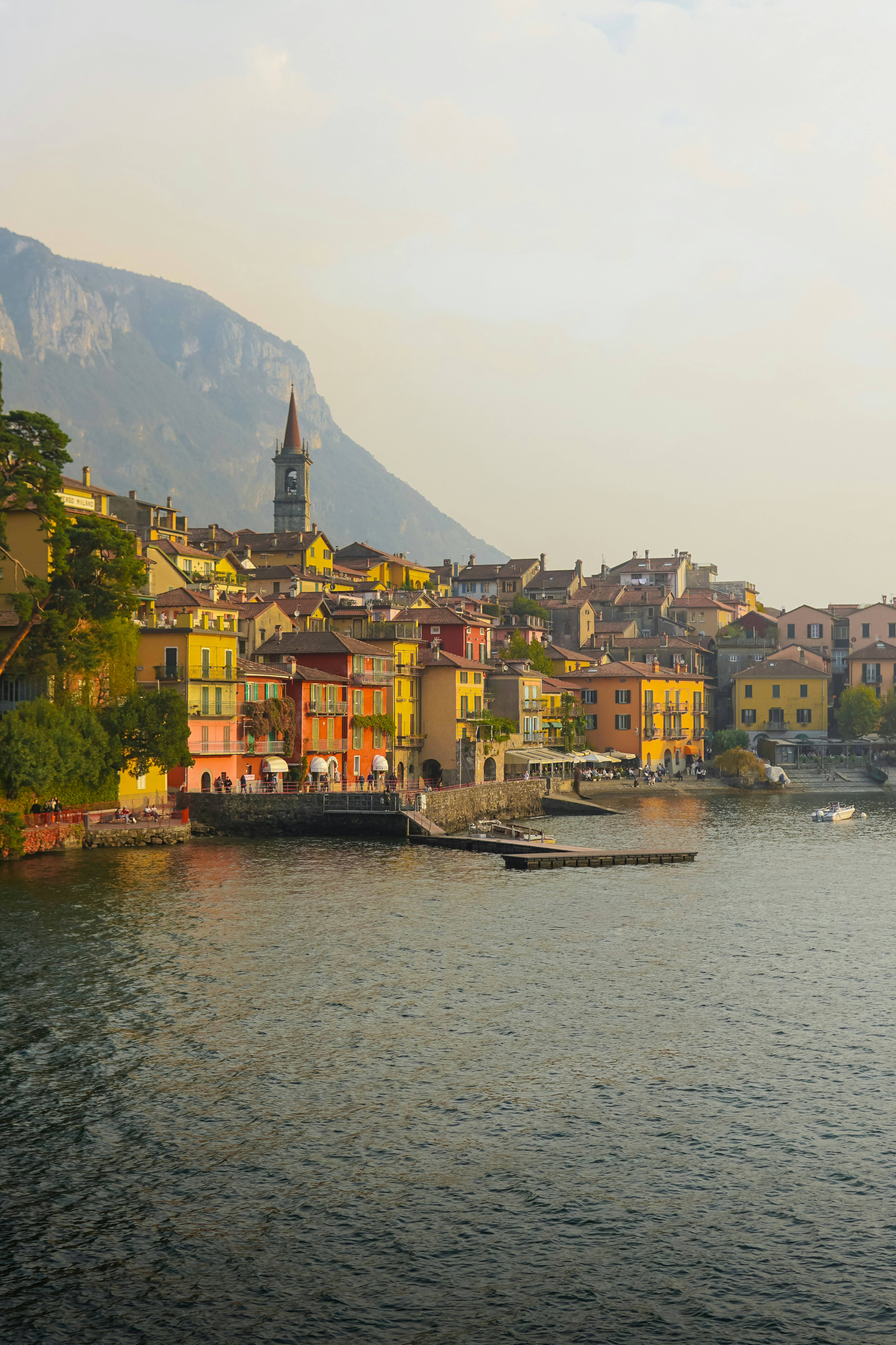 Colorful buildings line a lake with a mountain backdrop.