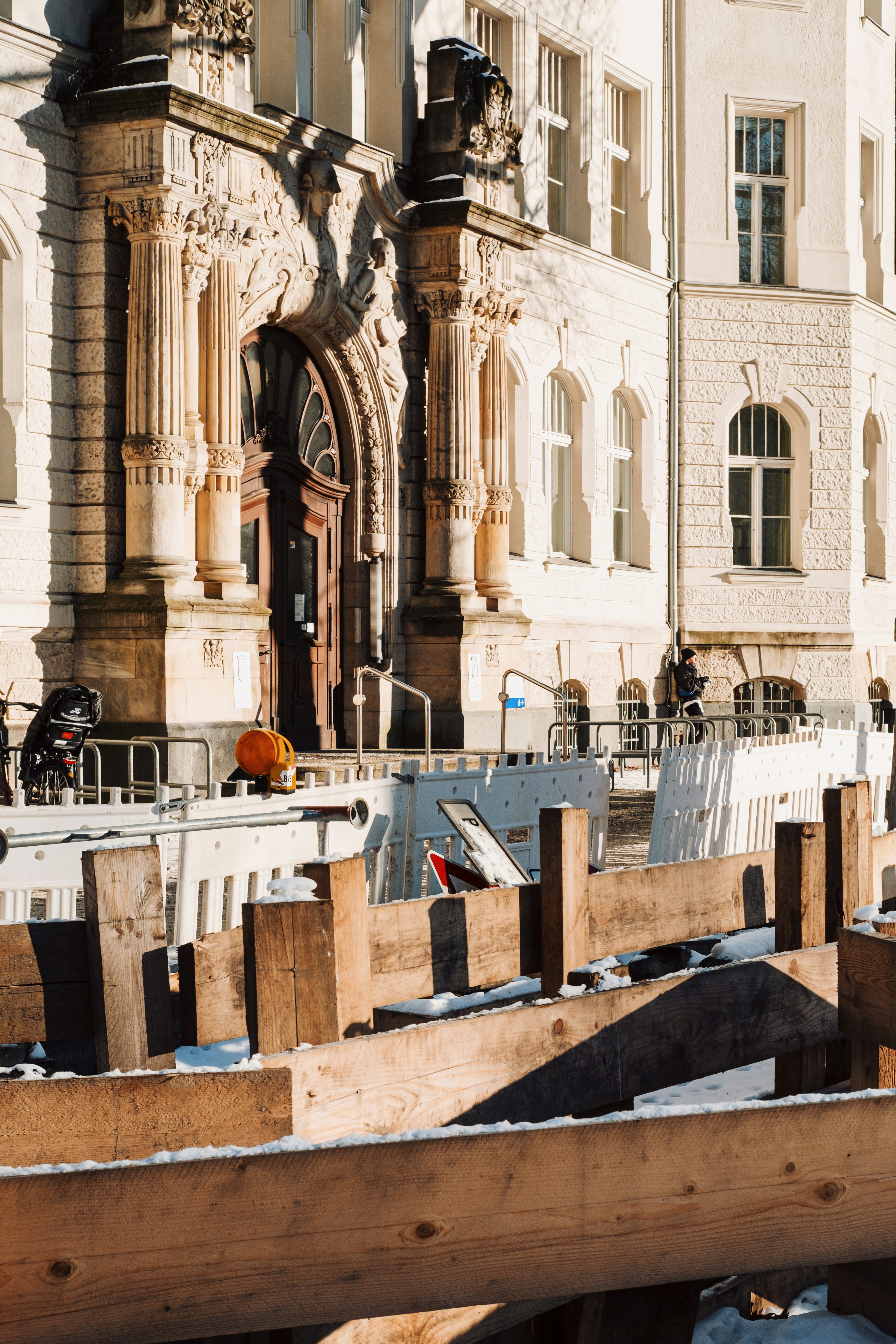Building under construction with wooden barriers and white barriers.
