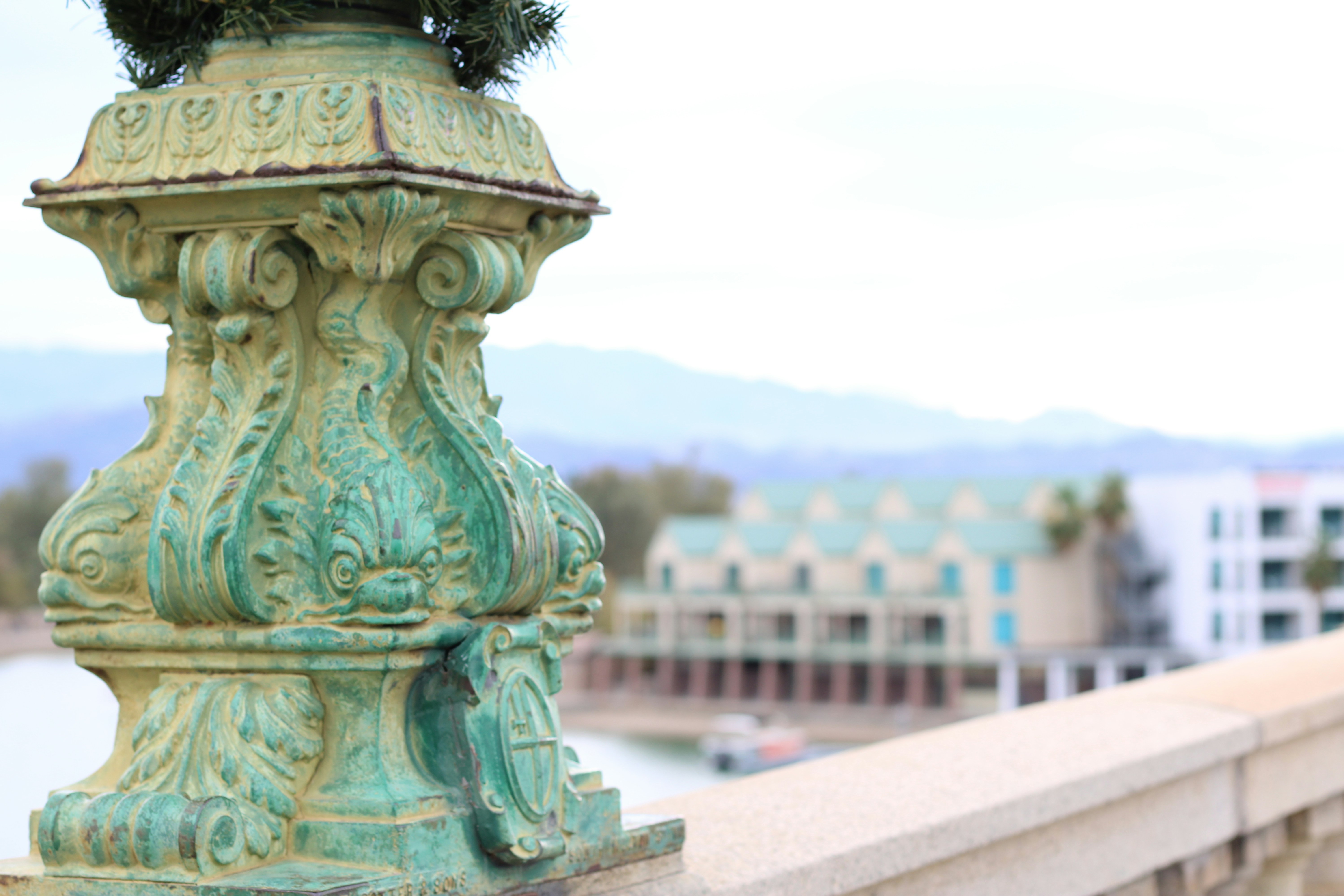Ornate green metal post with blurred buildings background
