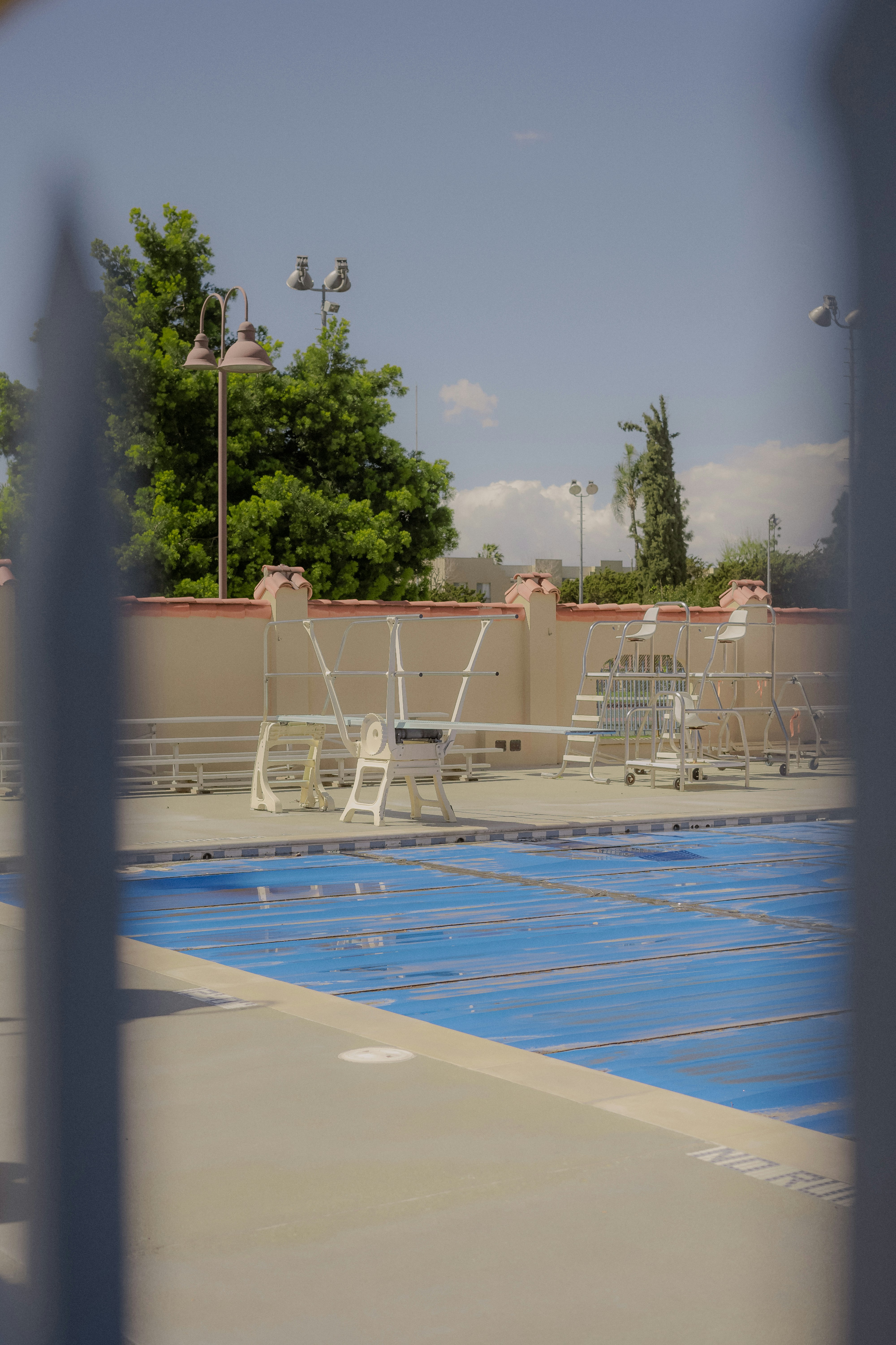 Empty swimming pool with blue cover and white diving boards.