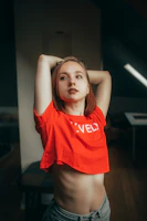 Young woman in red crop top with arms raised
