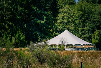 A large white tent set up in a grassy field.