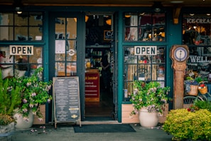 Green storefront with open signs and plants