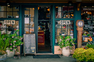 Green storefront with open signs and plants