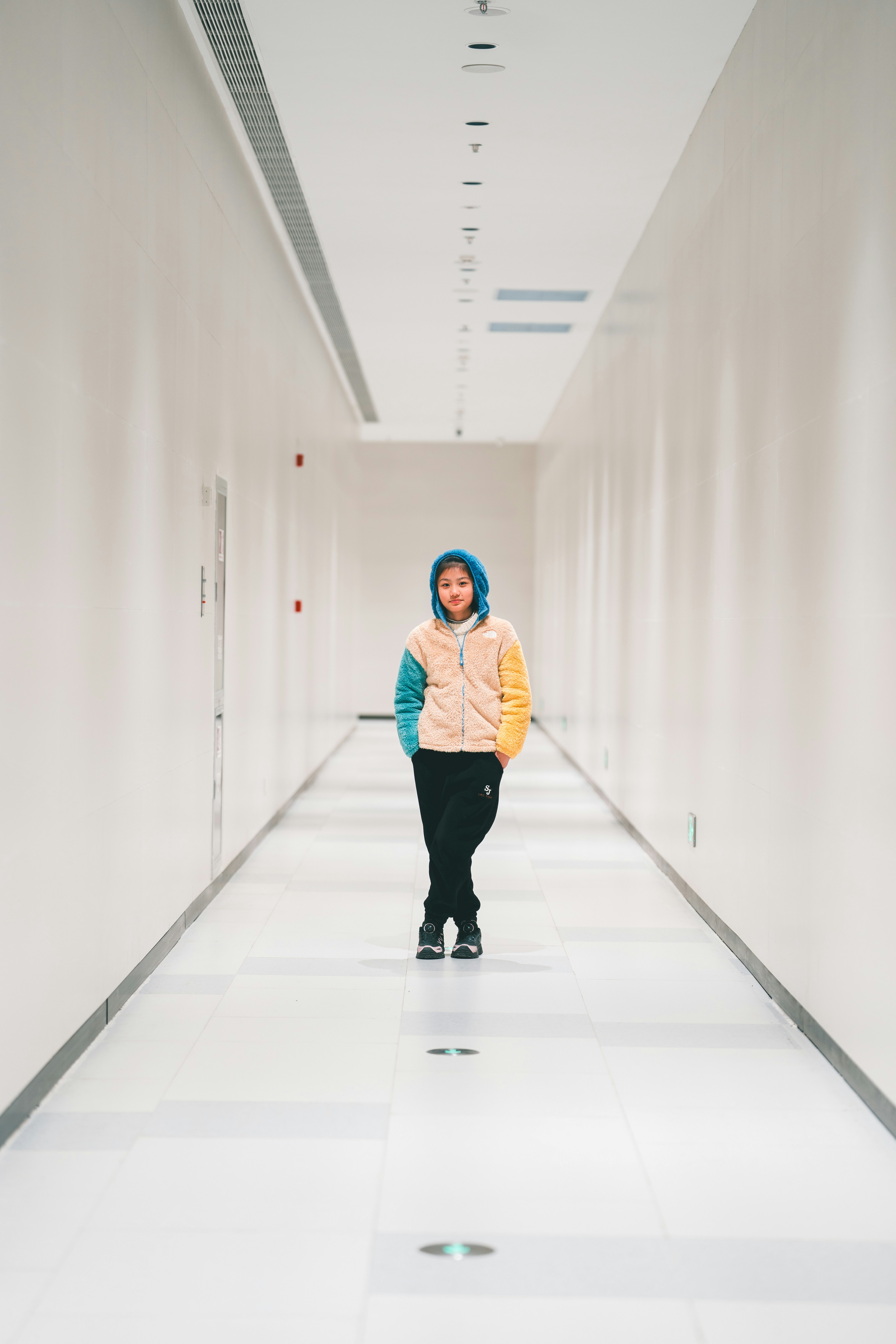 Una persona si trova in un corridoio vuoto e illuminato.