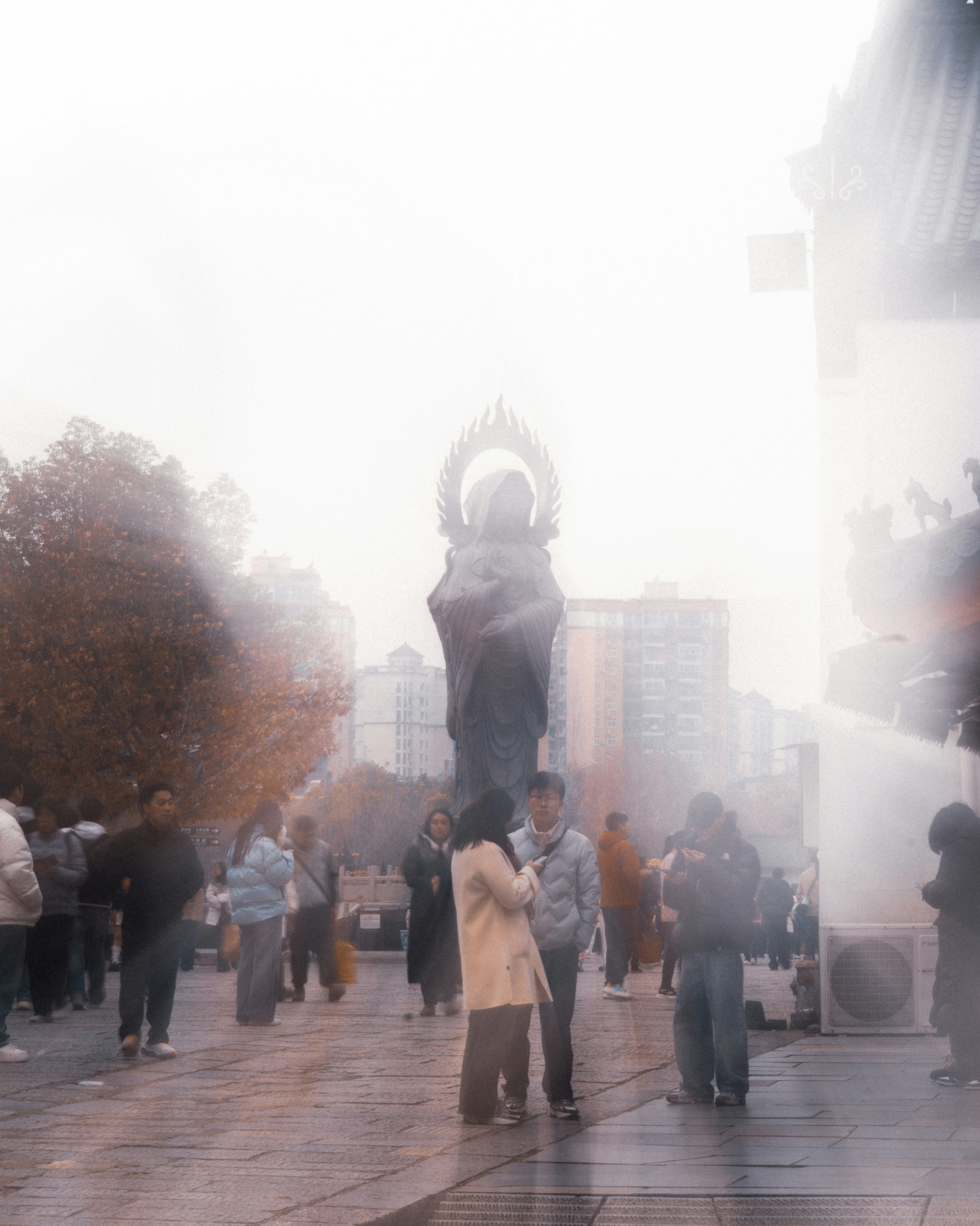People gather near a large statue in a plaza.