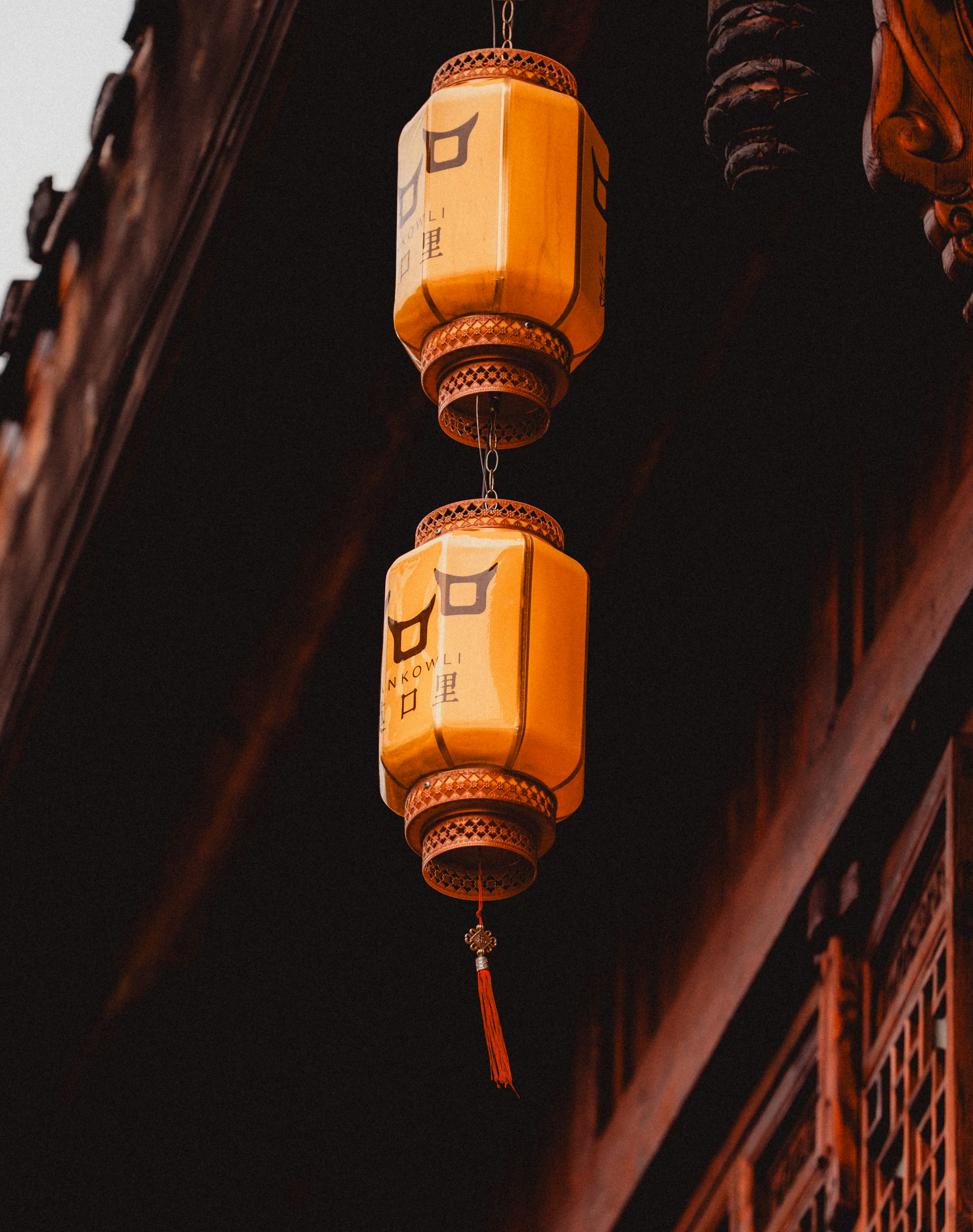 Two yellow lanterns hang from a building