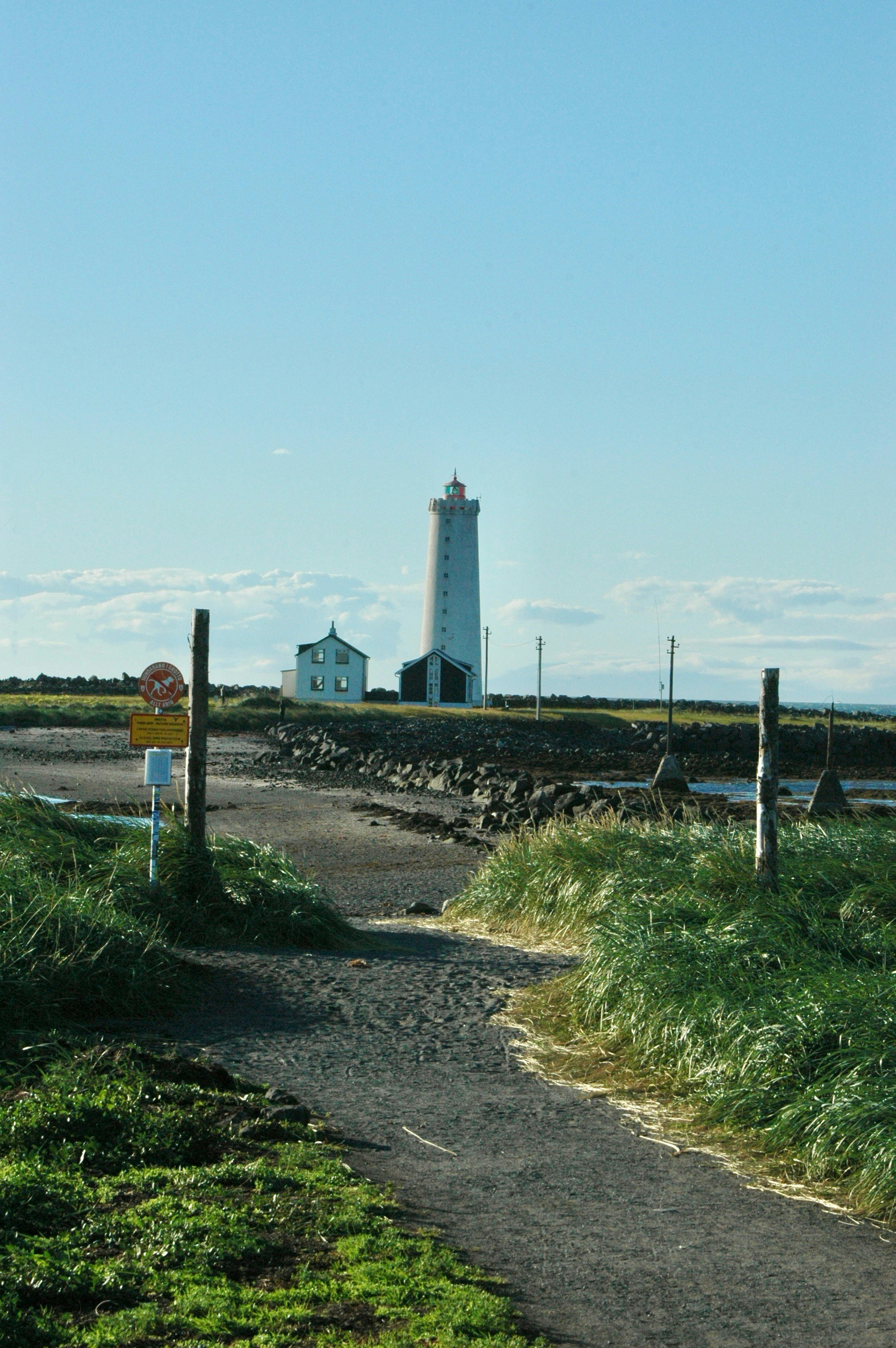 Tall white lighthouse with a small house nearby