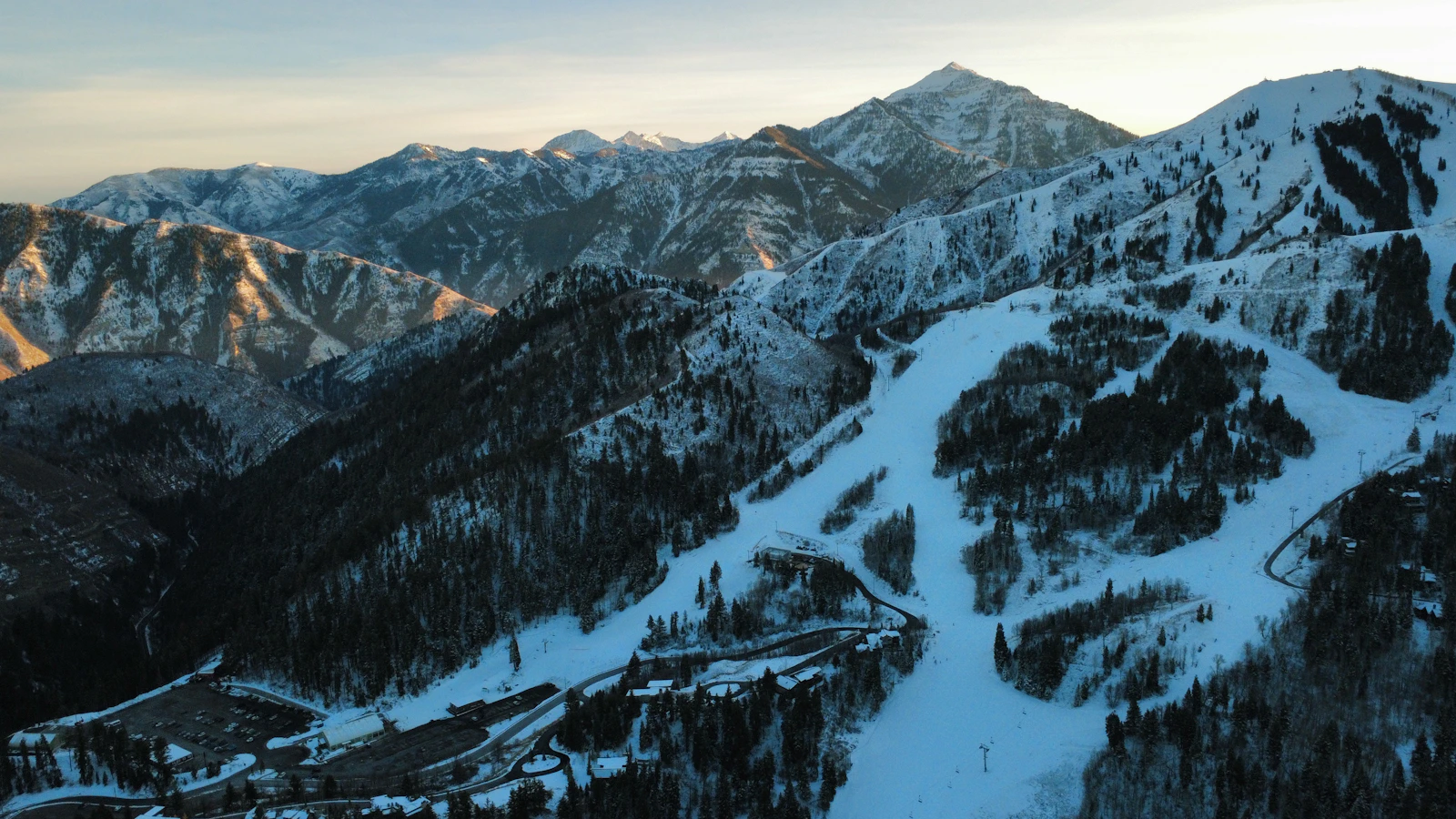 Marked ski runs cross a snow-covered mountain at sunrise.