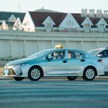 A silver taxi driving on a street.