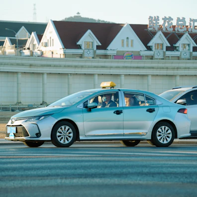 A silver taxi driving on a street.