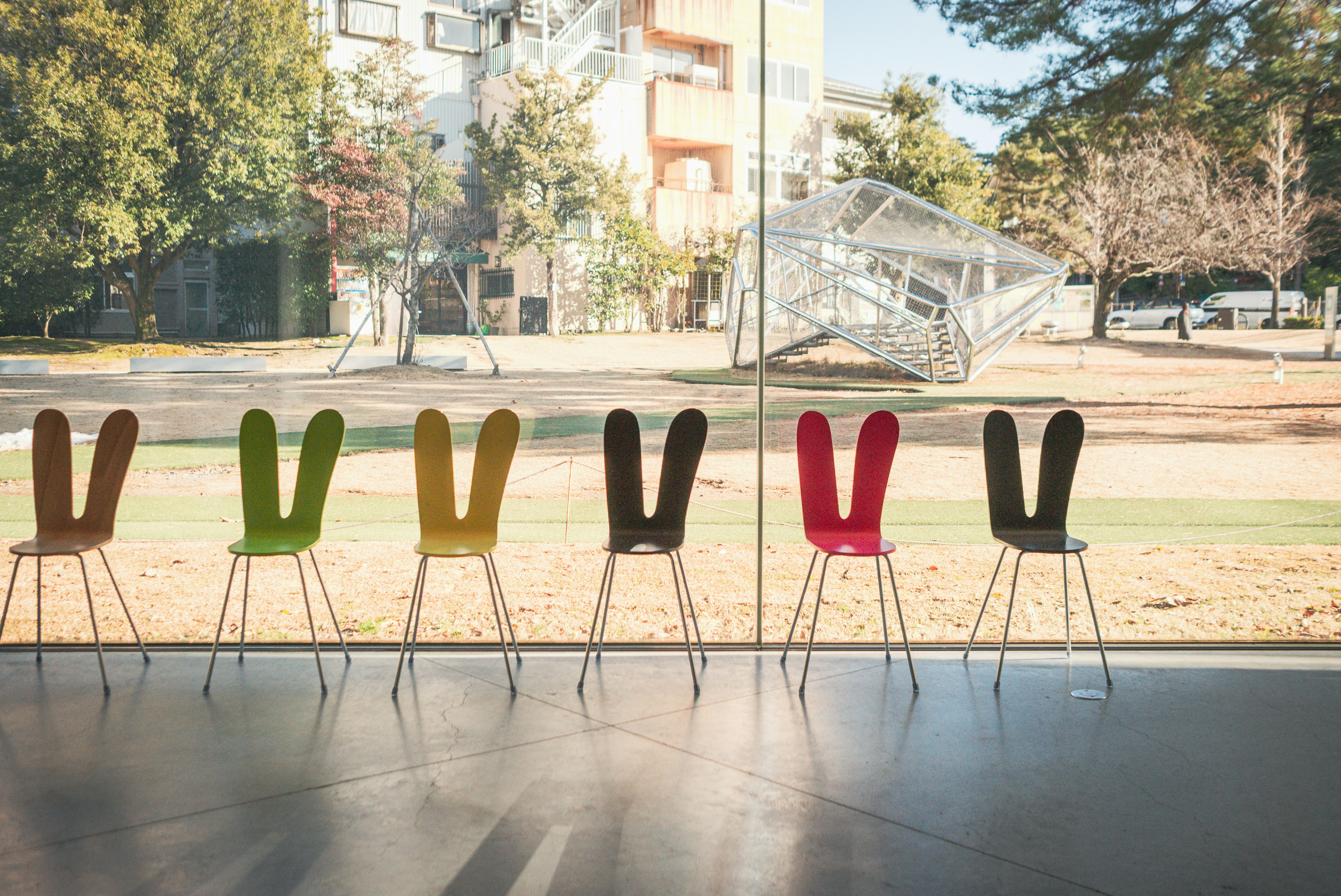 Seven colorful chairs with bunny ears arranged in a row.