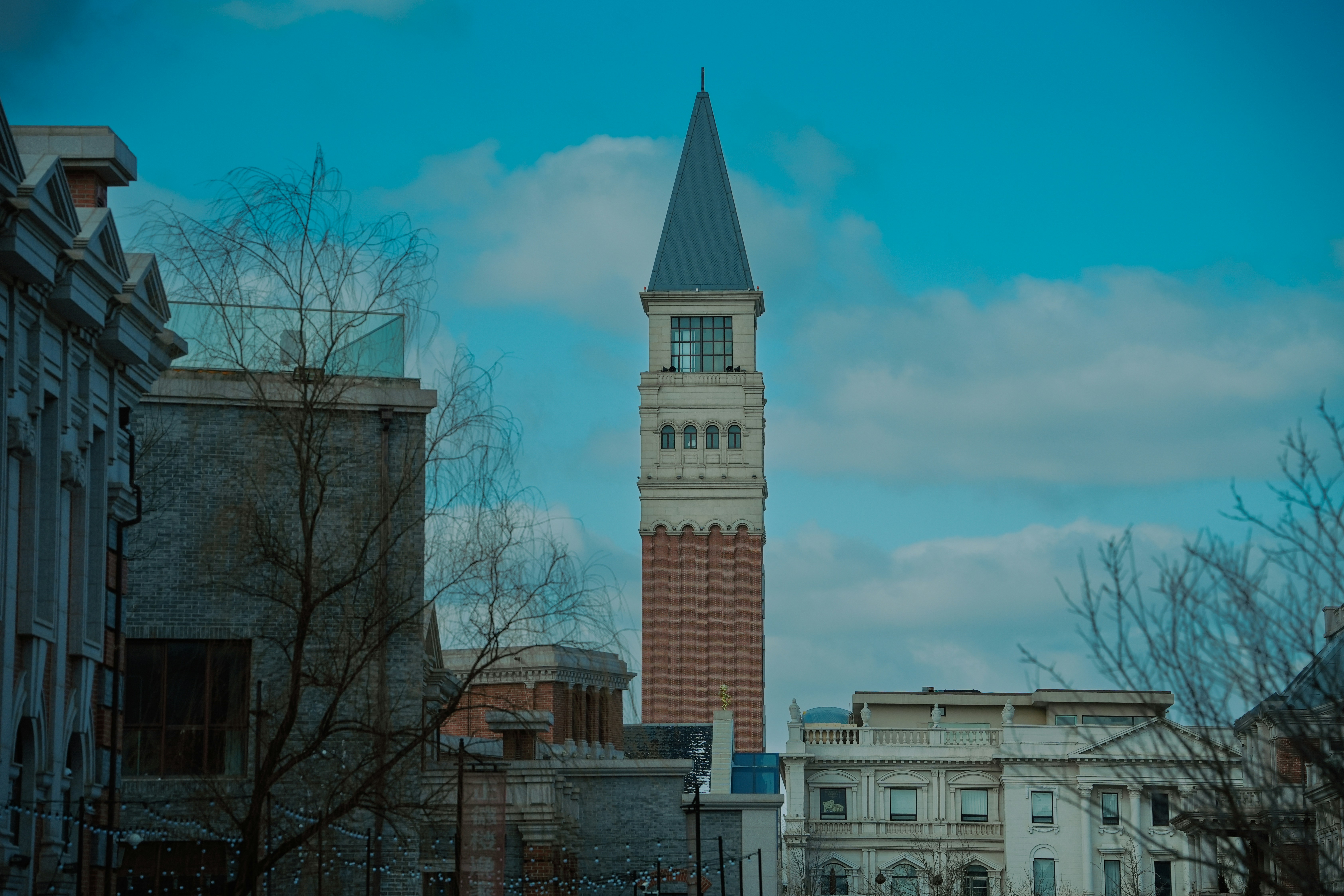 Tall brick tower with a pointed roof against sky