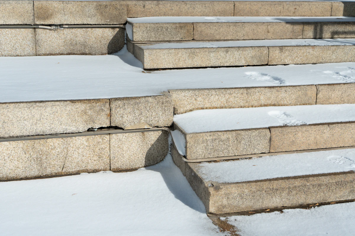 Stone front steps with cracks and a dusting of snow
