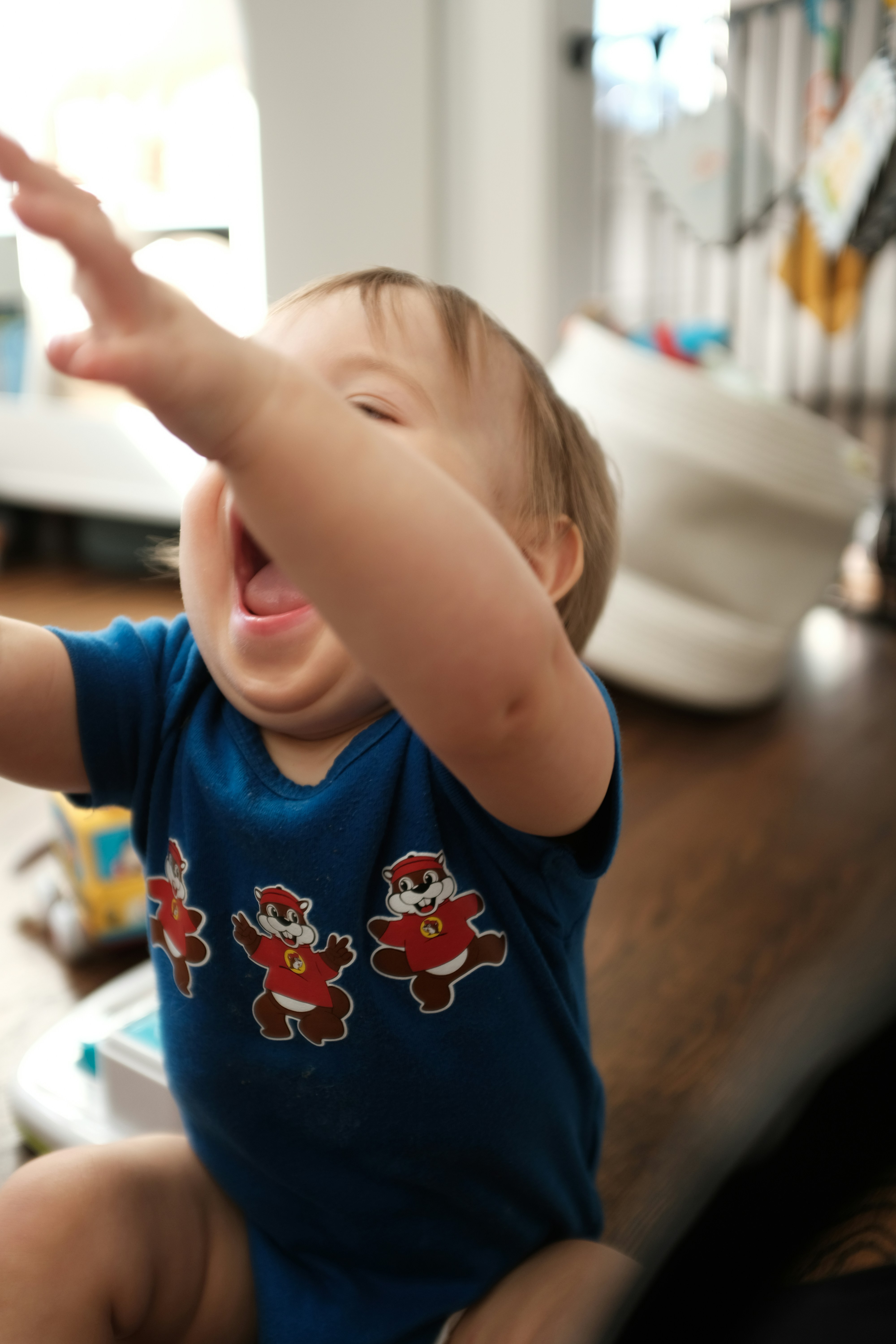 A laughing baby in a blue shirt with cartoon characters.