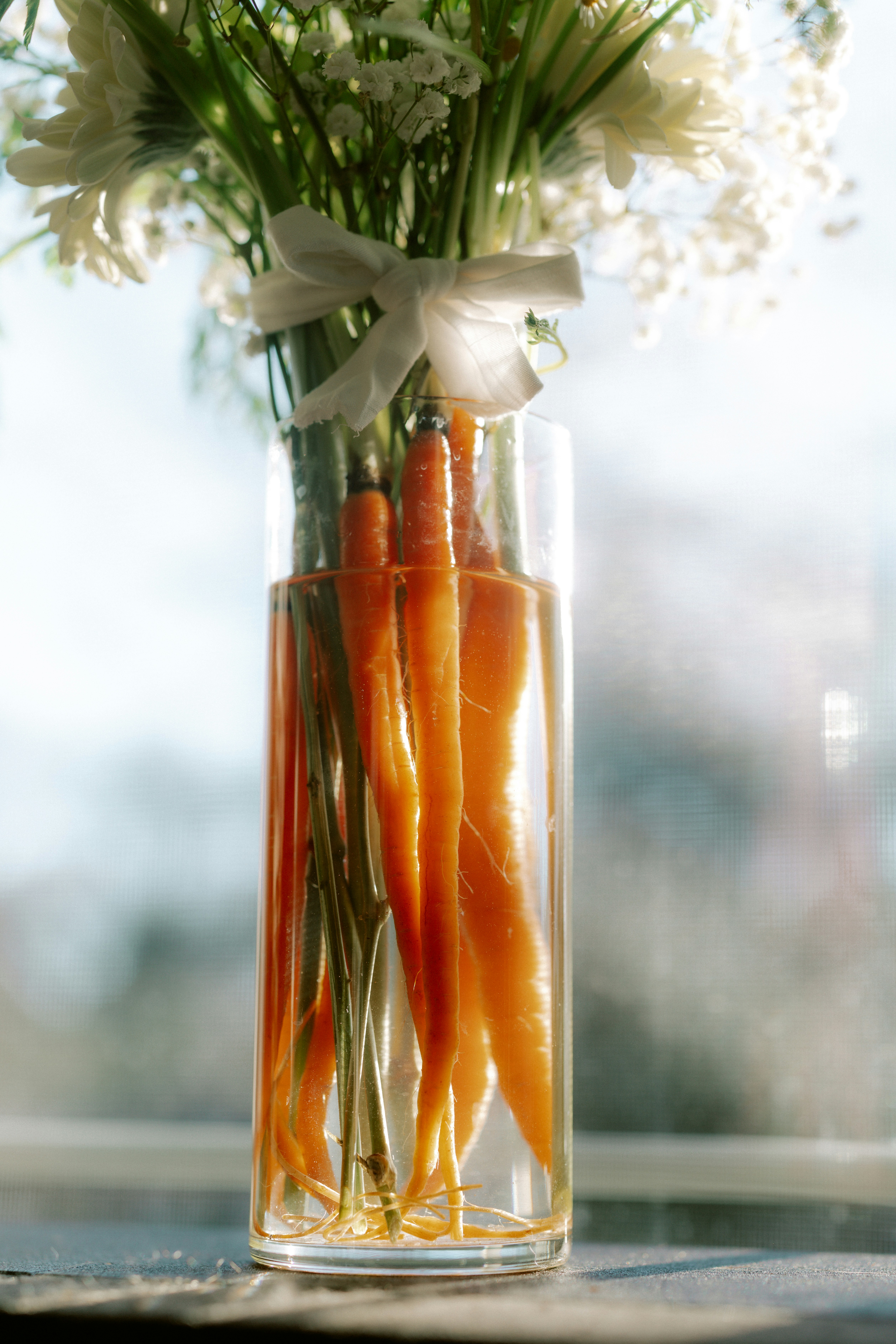 Carrots and flowers in a glass vase