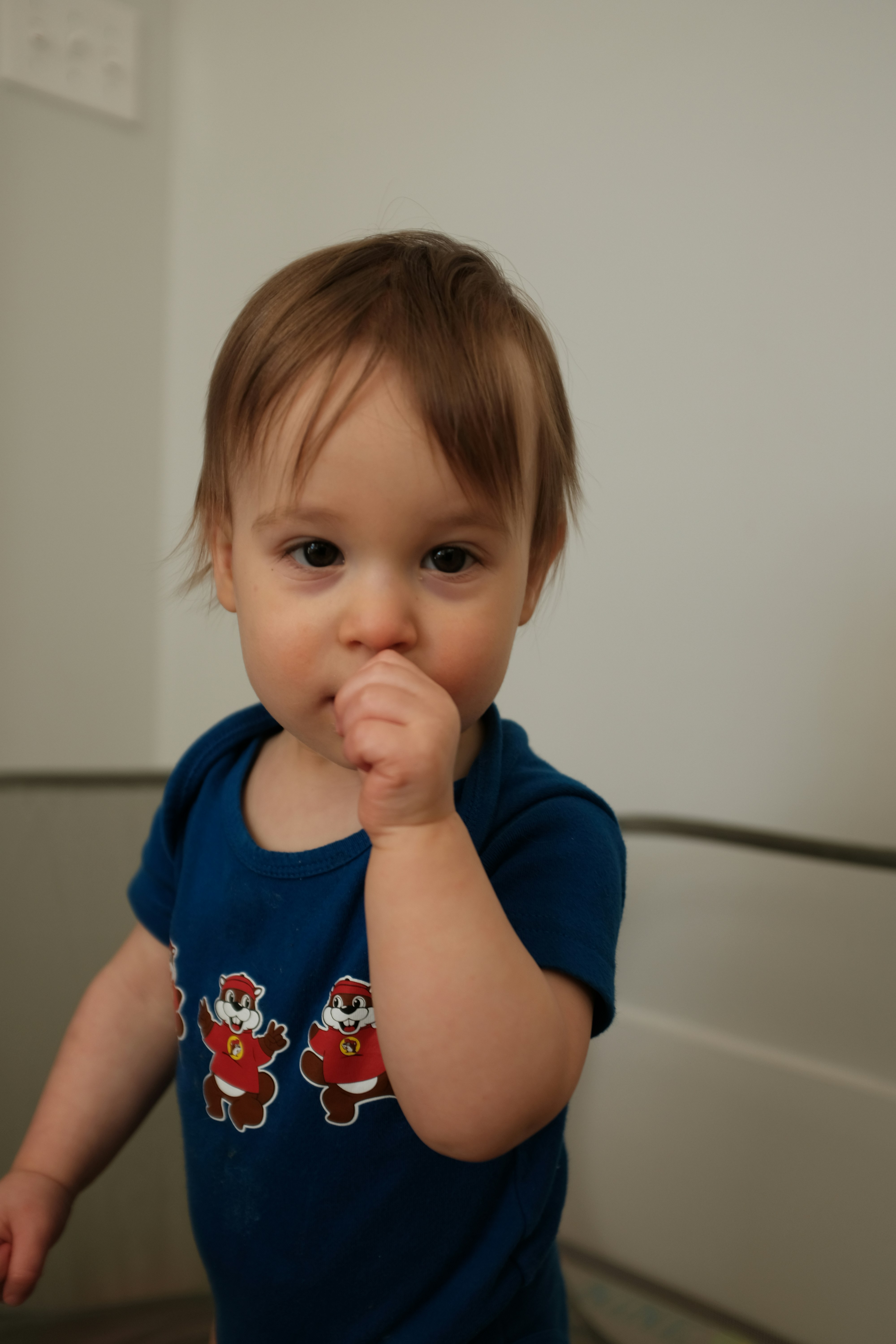 A young child wearing a blue onesie with cartoon characters.