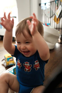 A laughing baby with hands raised in excitement