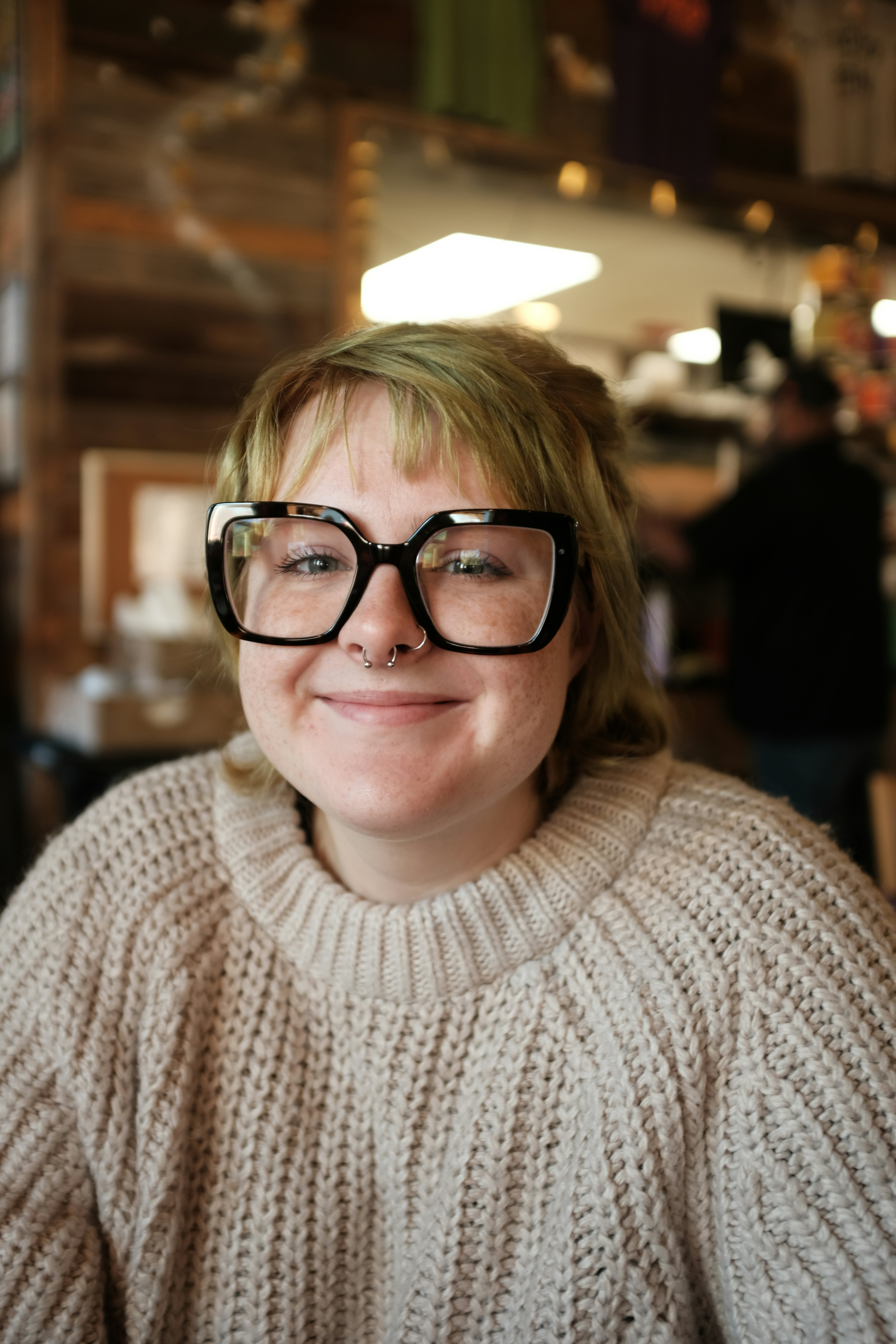 Young woman with glasses and nose ring smiles