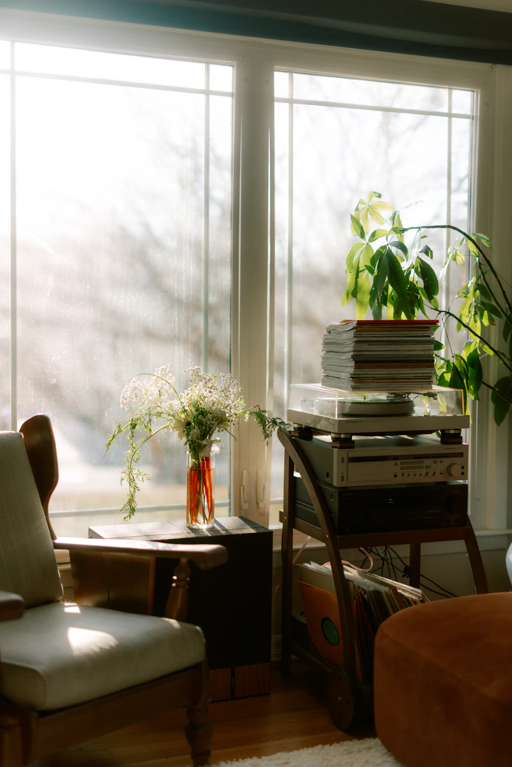 A cosy armchair by a bright window, with plants and flowers
