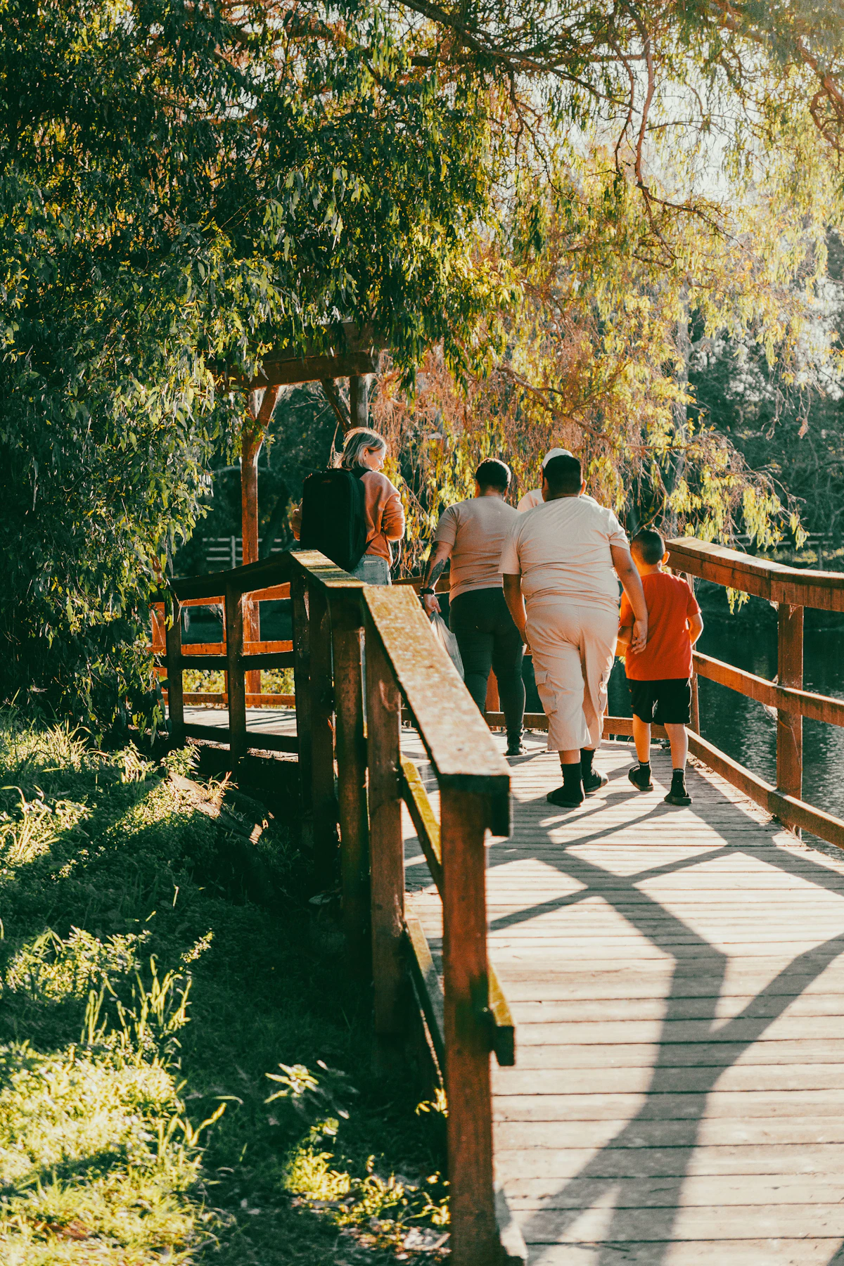A family crossing a wooden footbridge together in nature