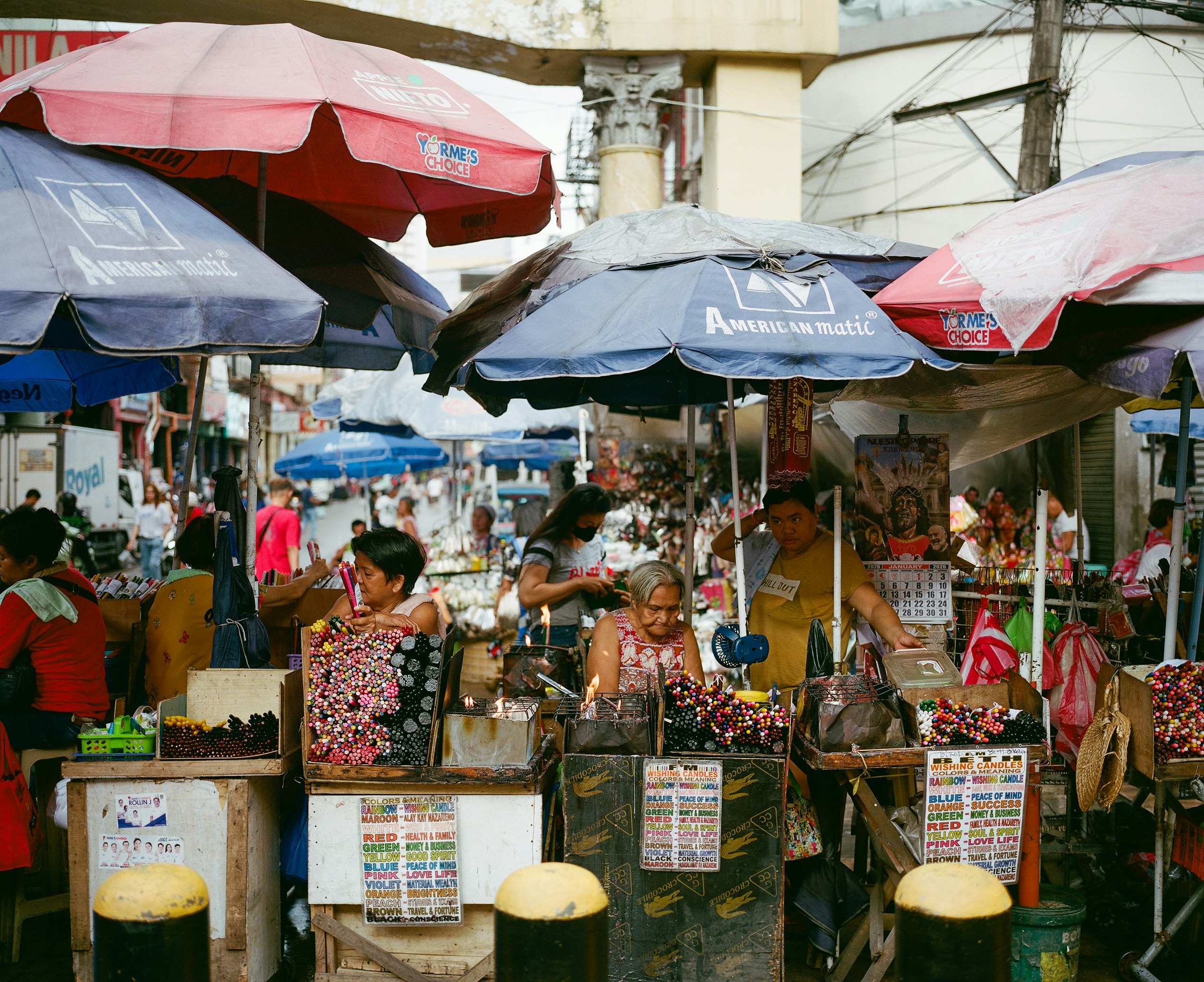 Busy outdoor market with vendors under umbrellas.