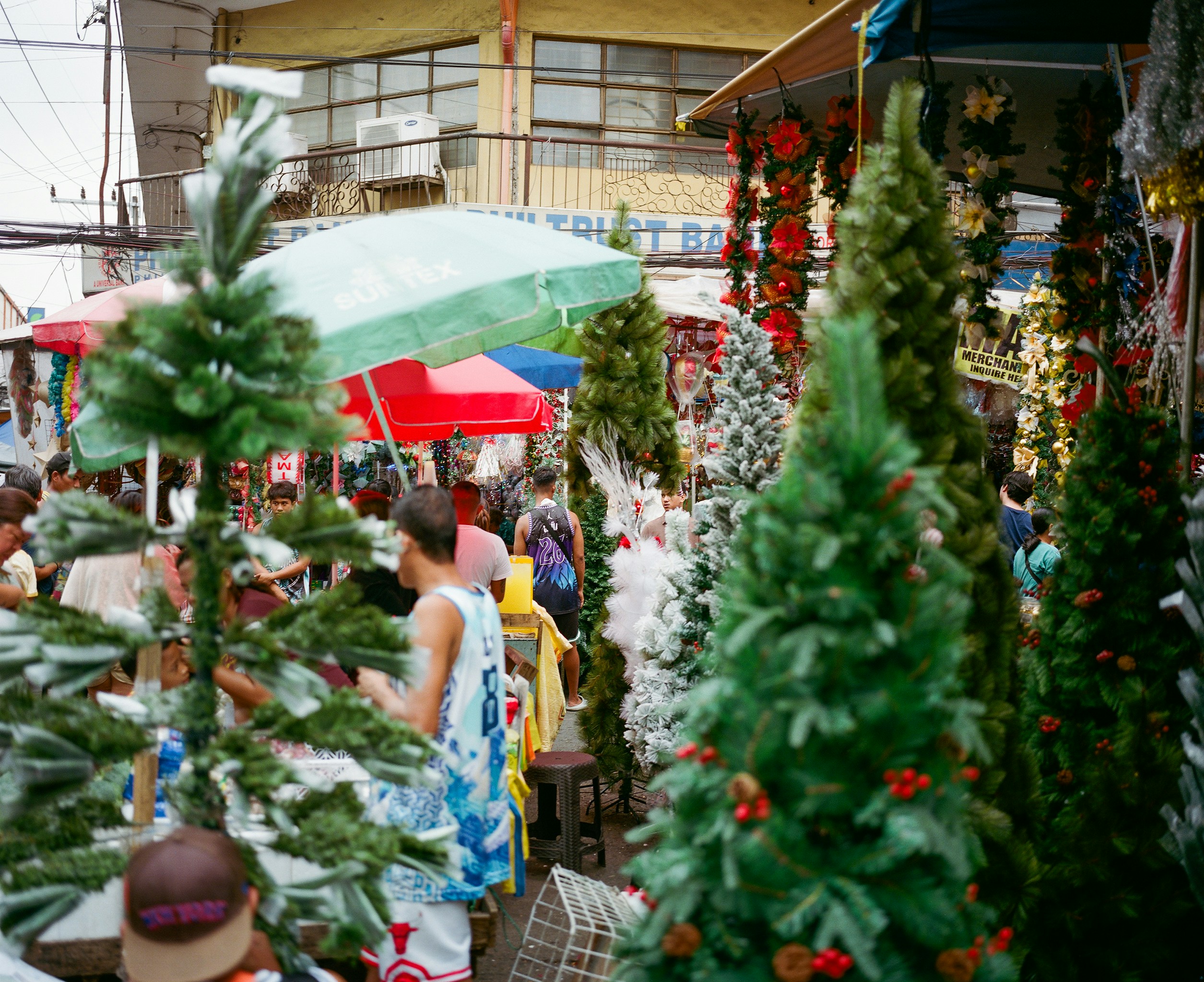 Artificial christmas trees displayed at an outdoor market.