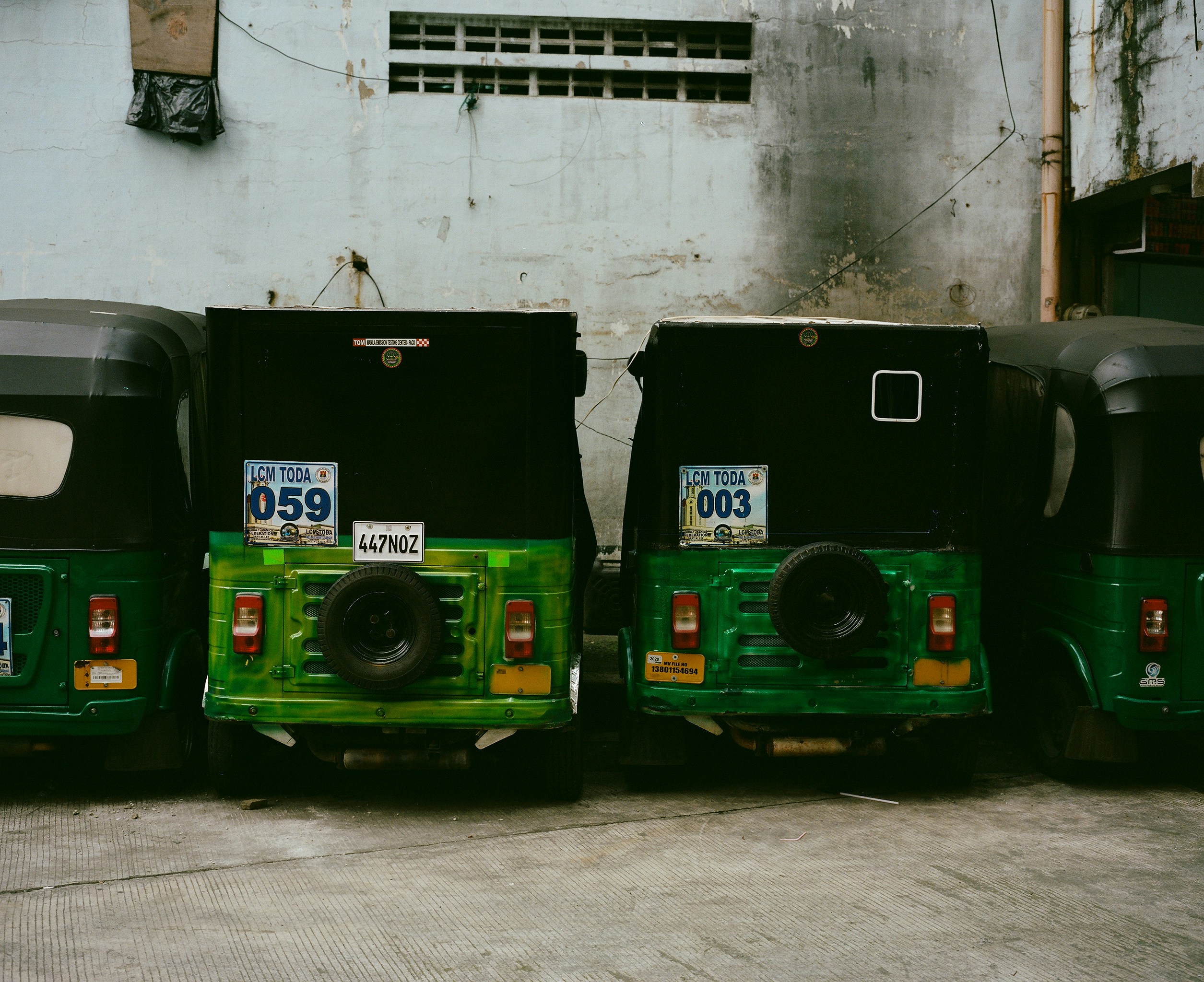 Two green auto rickshaws parked in a row.