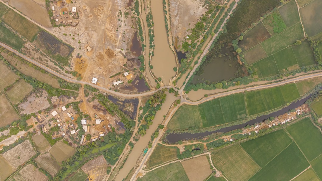 A close-up shot of a group of villagers, including farmers, looking distressed and pointing towards a map or a distant land, with a partially constructed road in the background.