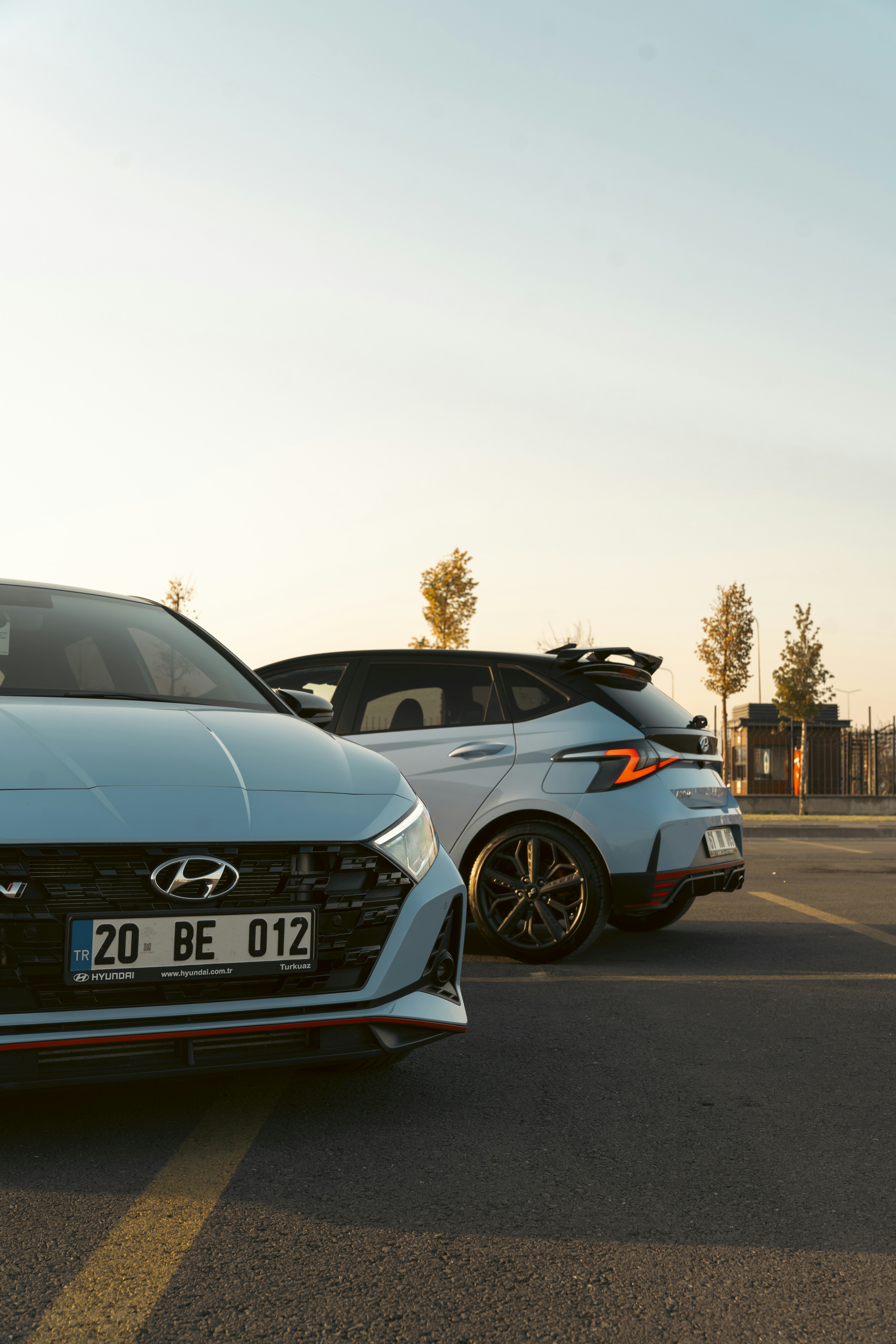Two light blue cars parked outdoors at sunset.