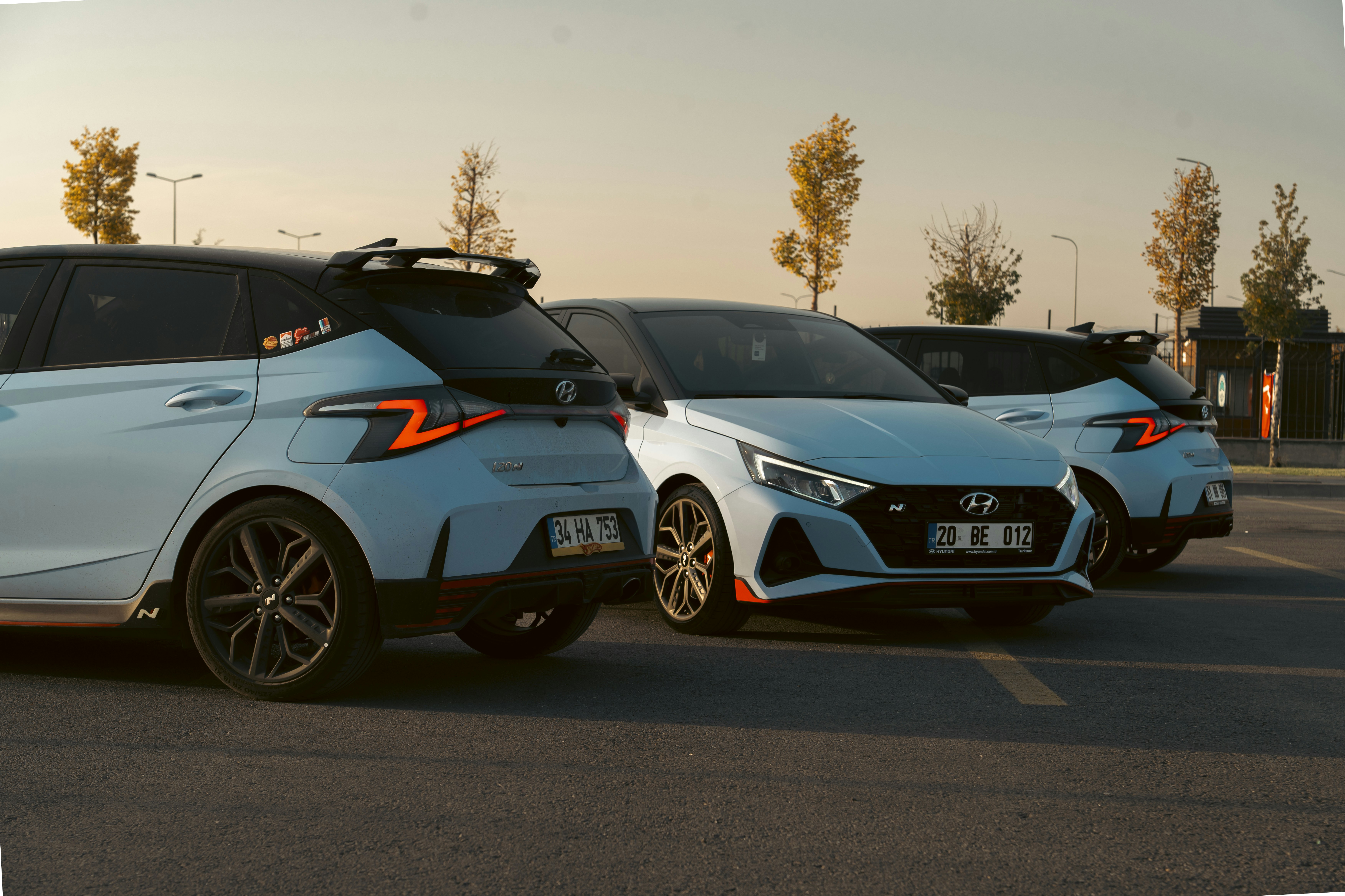 Three white cars parked in a lot at sunset