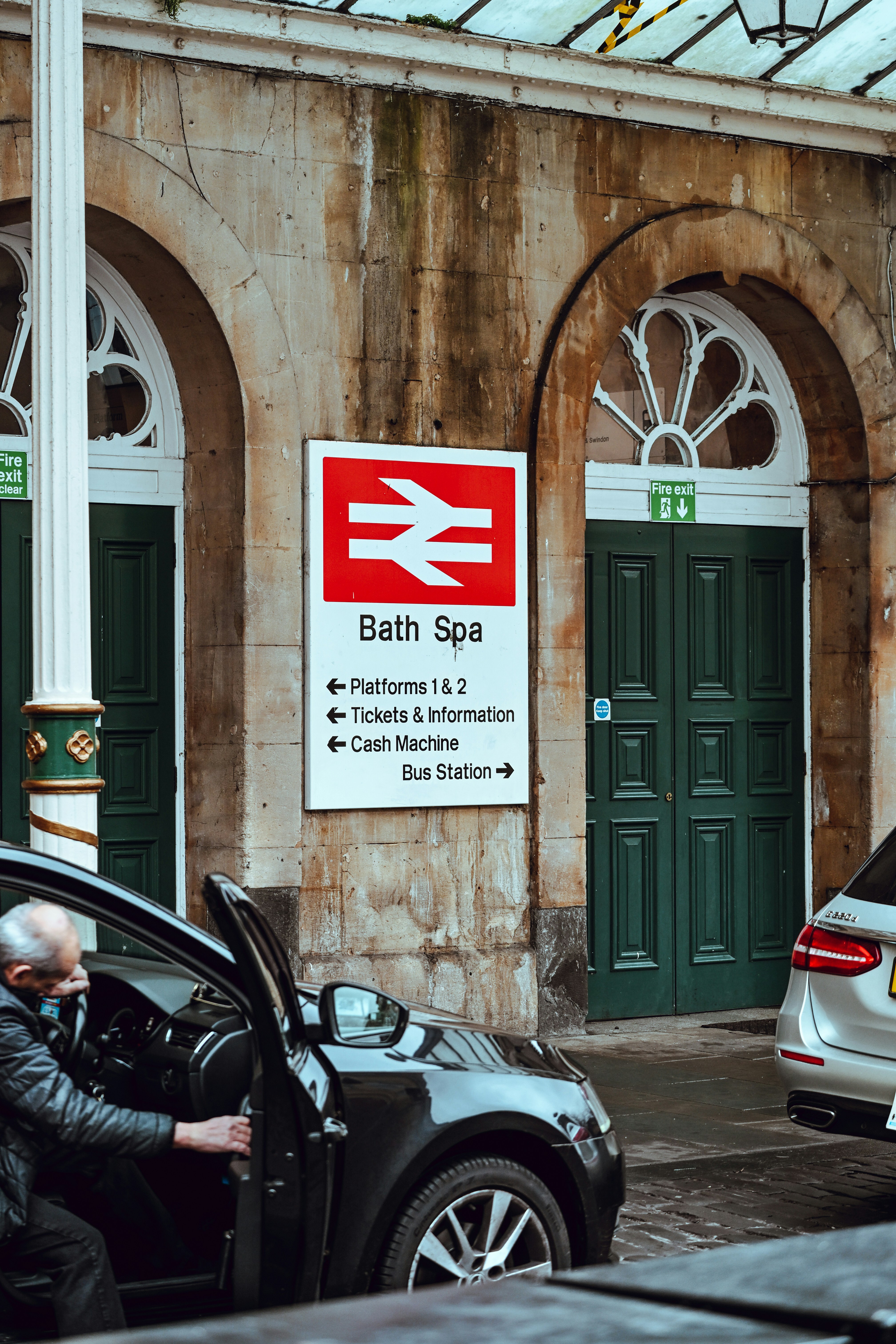 Homem entrando no carro na entrada da estação de trem de Bath Spa