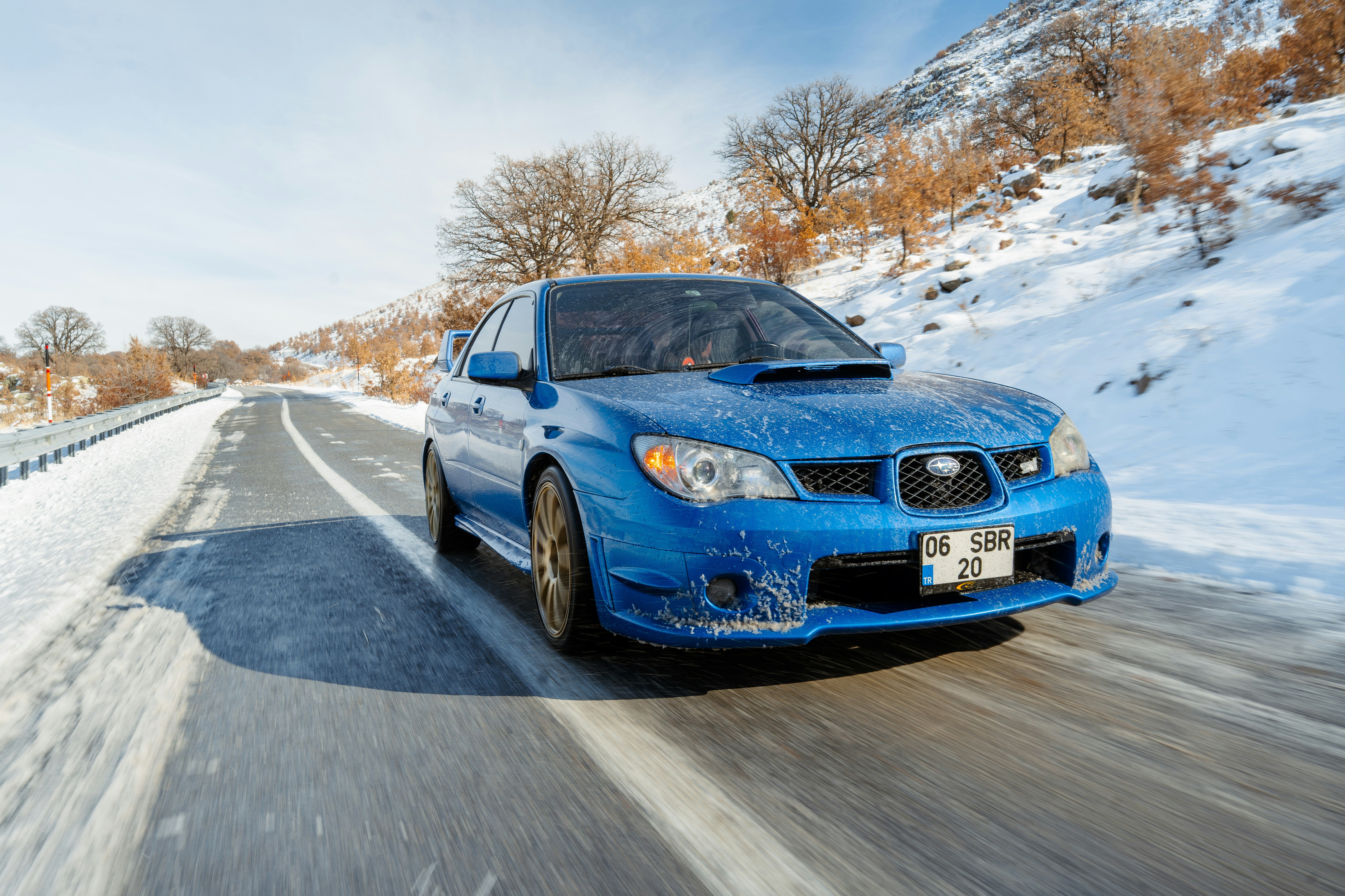 Blue subaru driving on a snowy road