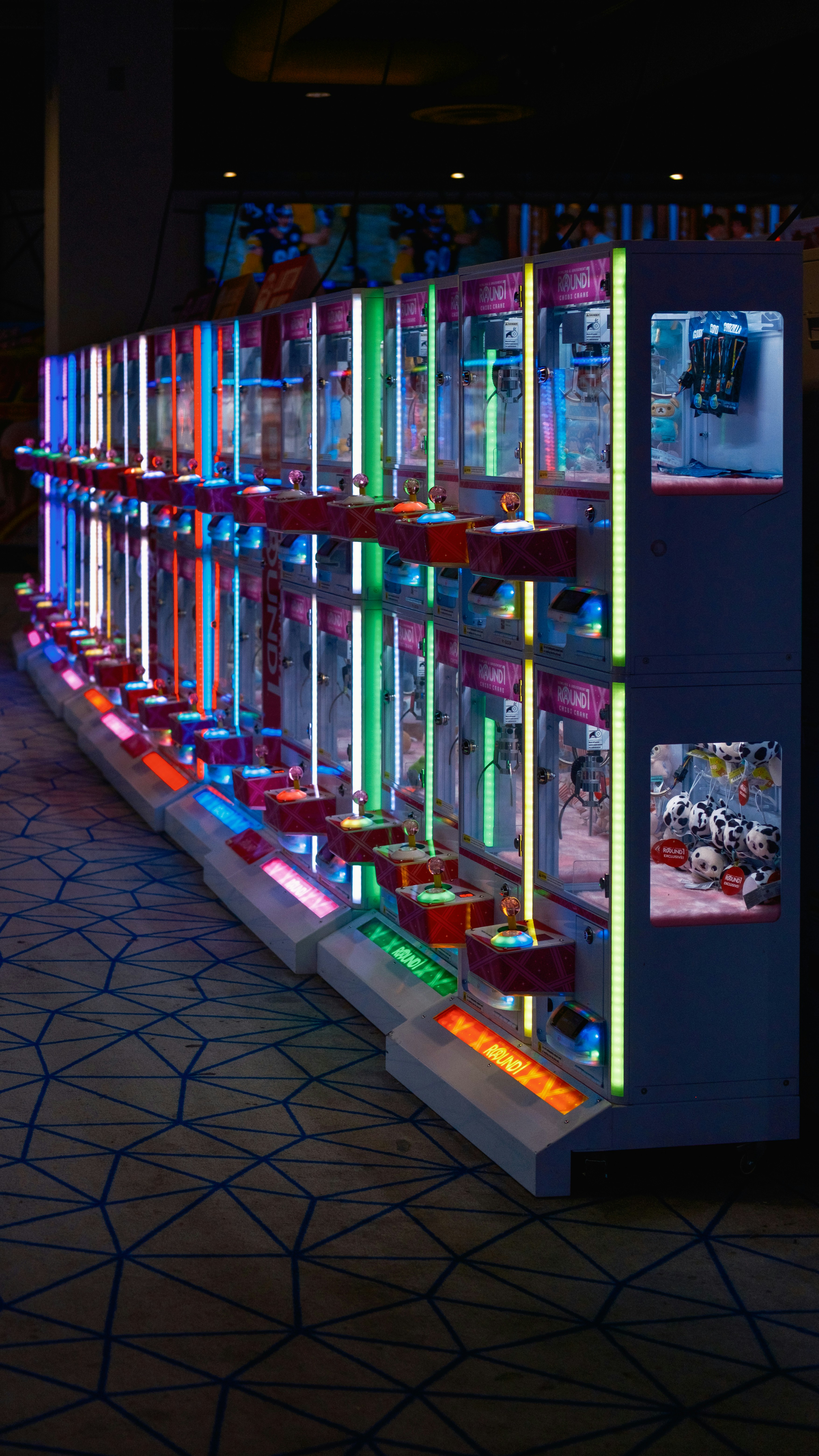 Row of colorful arcade claw machines in dim lighting