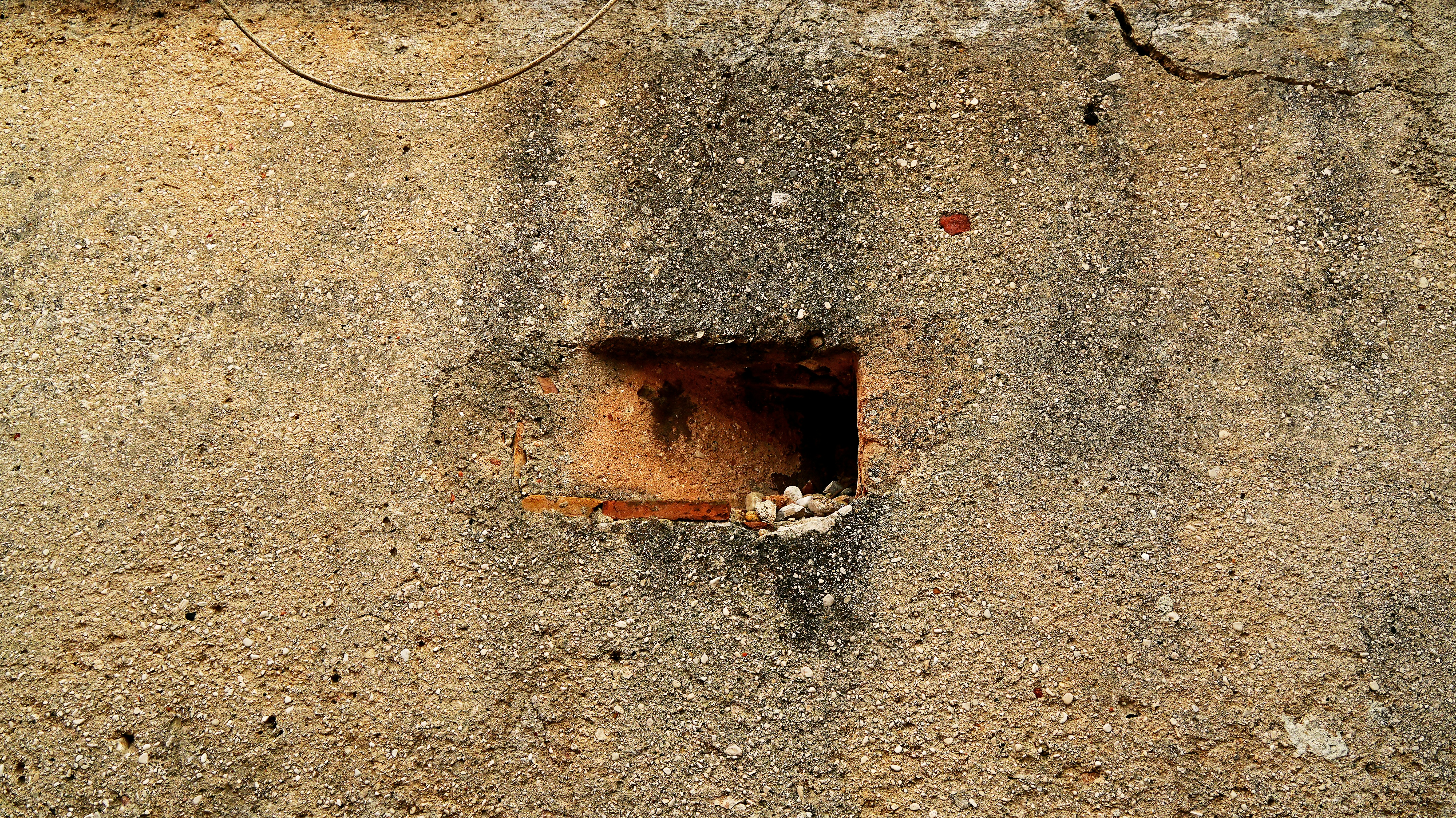 A rough concrete wall with a small opening.