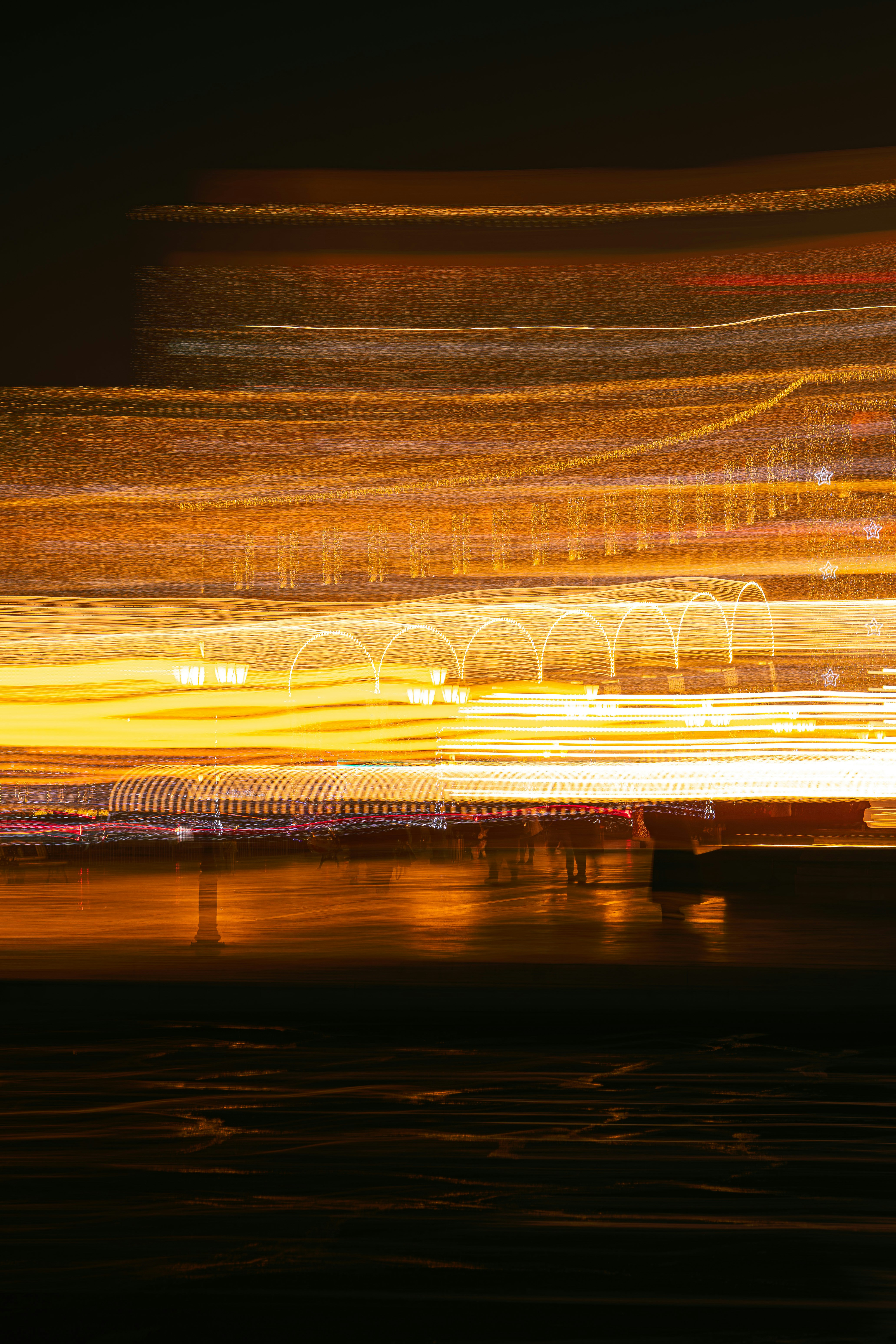 Abstract light streaks over dark water at night