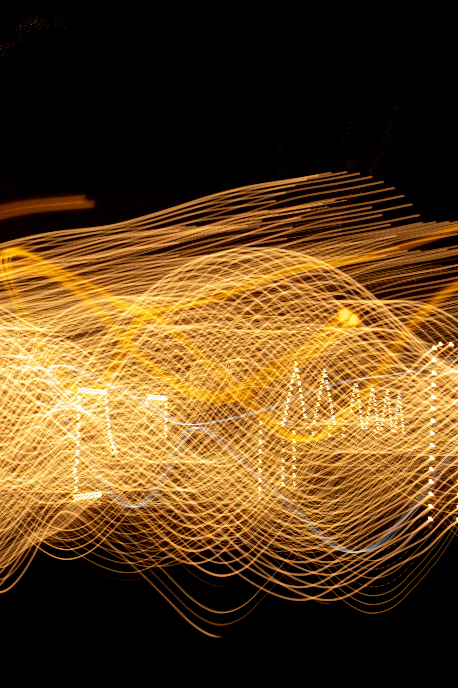 Abstract golden light trails streaking across a pure black background in a long-exposure sweep of fine luminous lines
