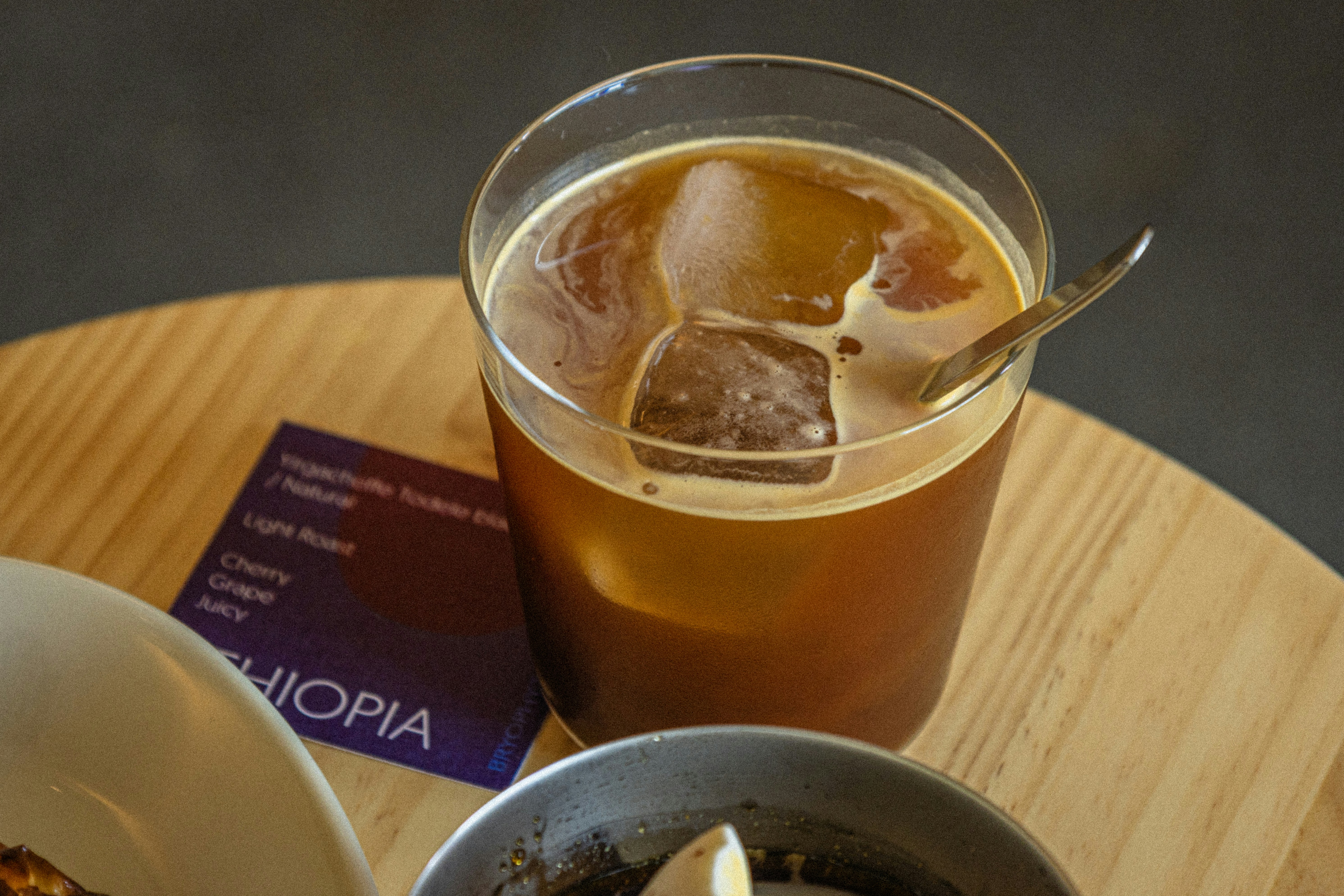 Iced coffee with ice cubes and spoon on table