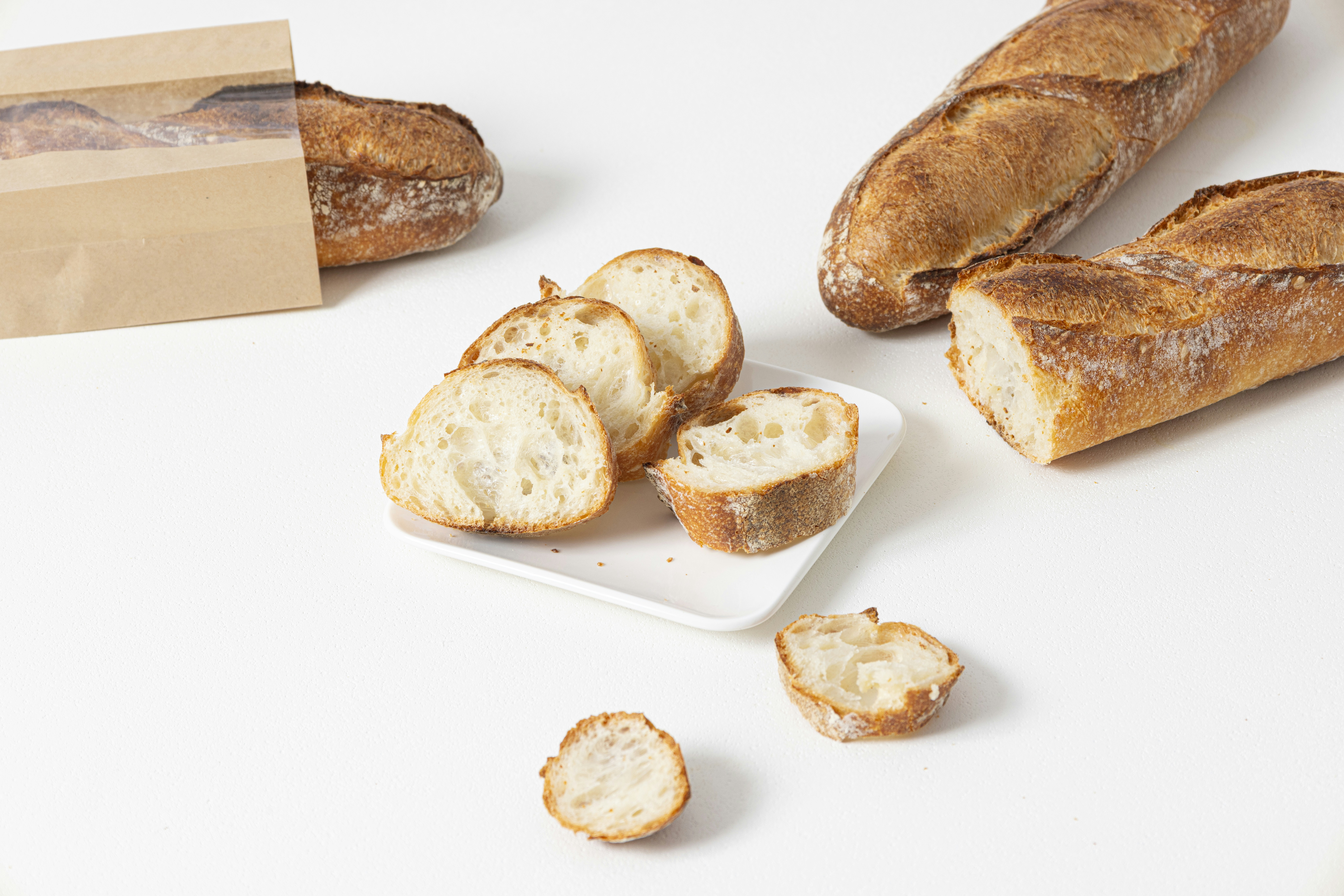 Freshly baked baguettes and slices on a white surface.