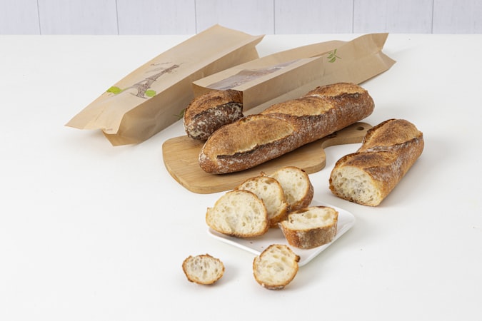 Several baguettes and sliced bread on a white surface.