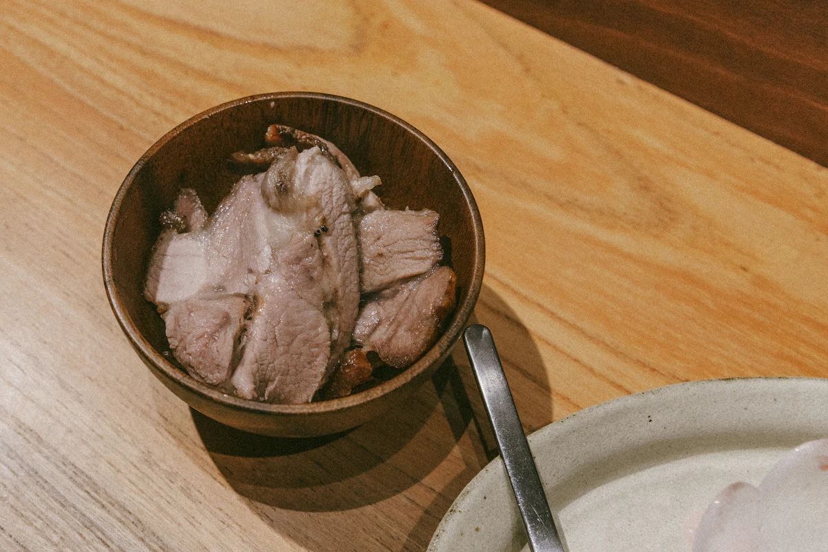 Sliced pork in a wooden bowl on a table