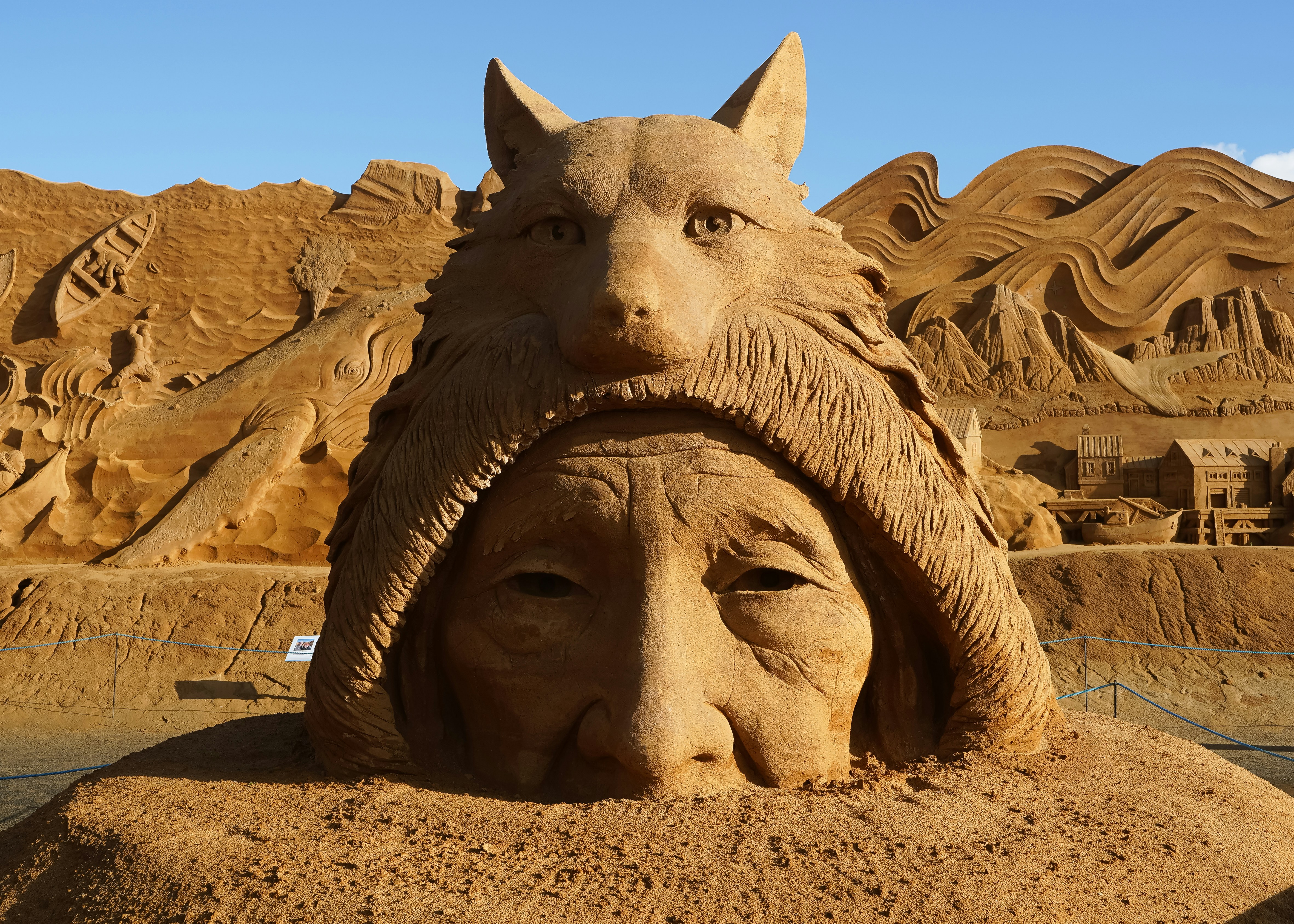 Sand sculpture of a person wearing a wolf headdress