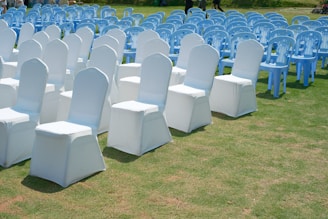 Rows of white and blue chairs set up on grass