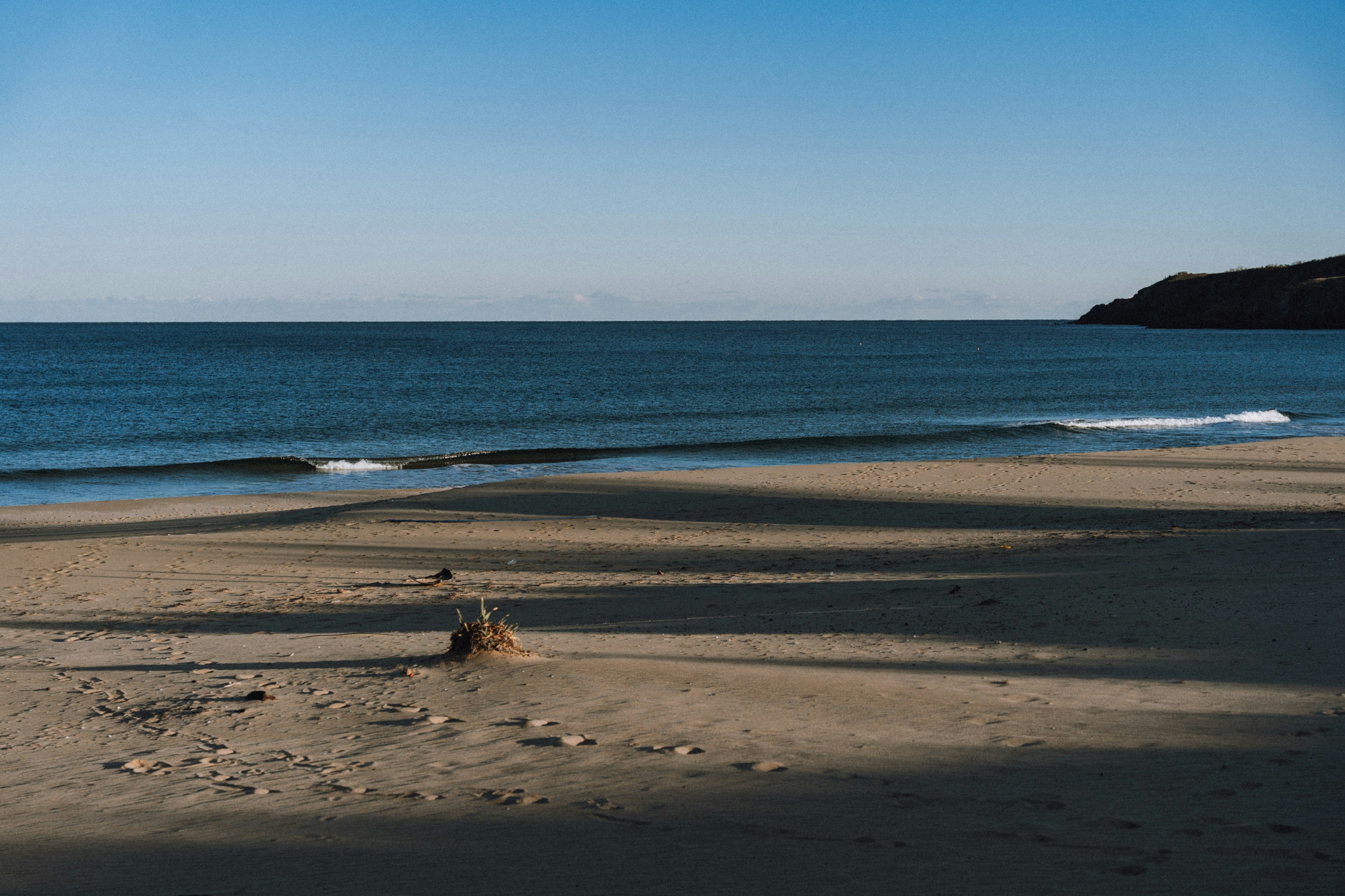 Sandy beach with gentle waves under a clear blue sky