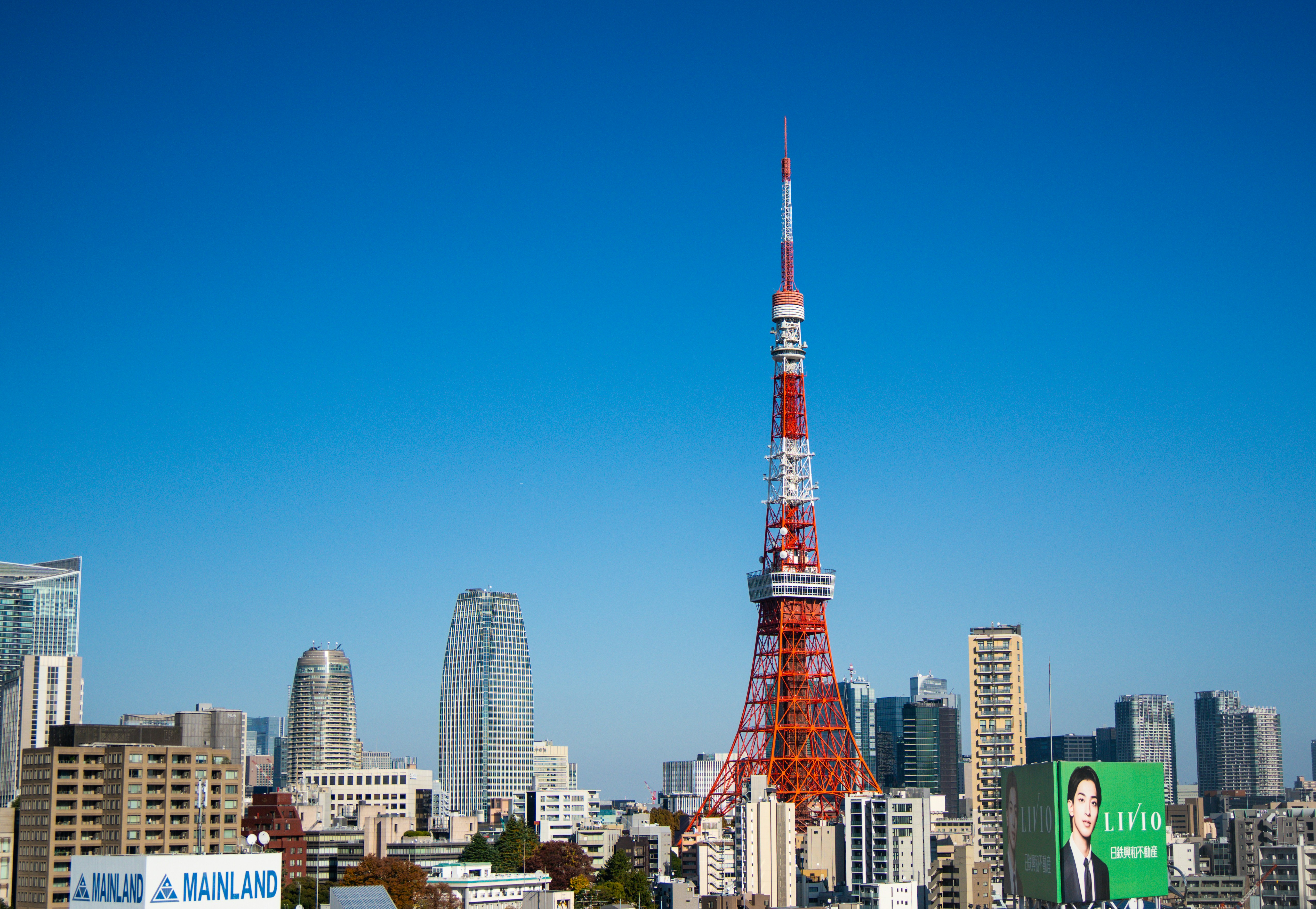 Tokyo tower stands tall amidst a cityscape under clear skies.