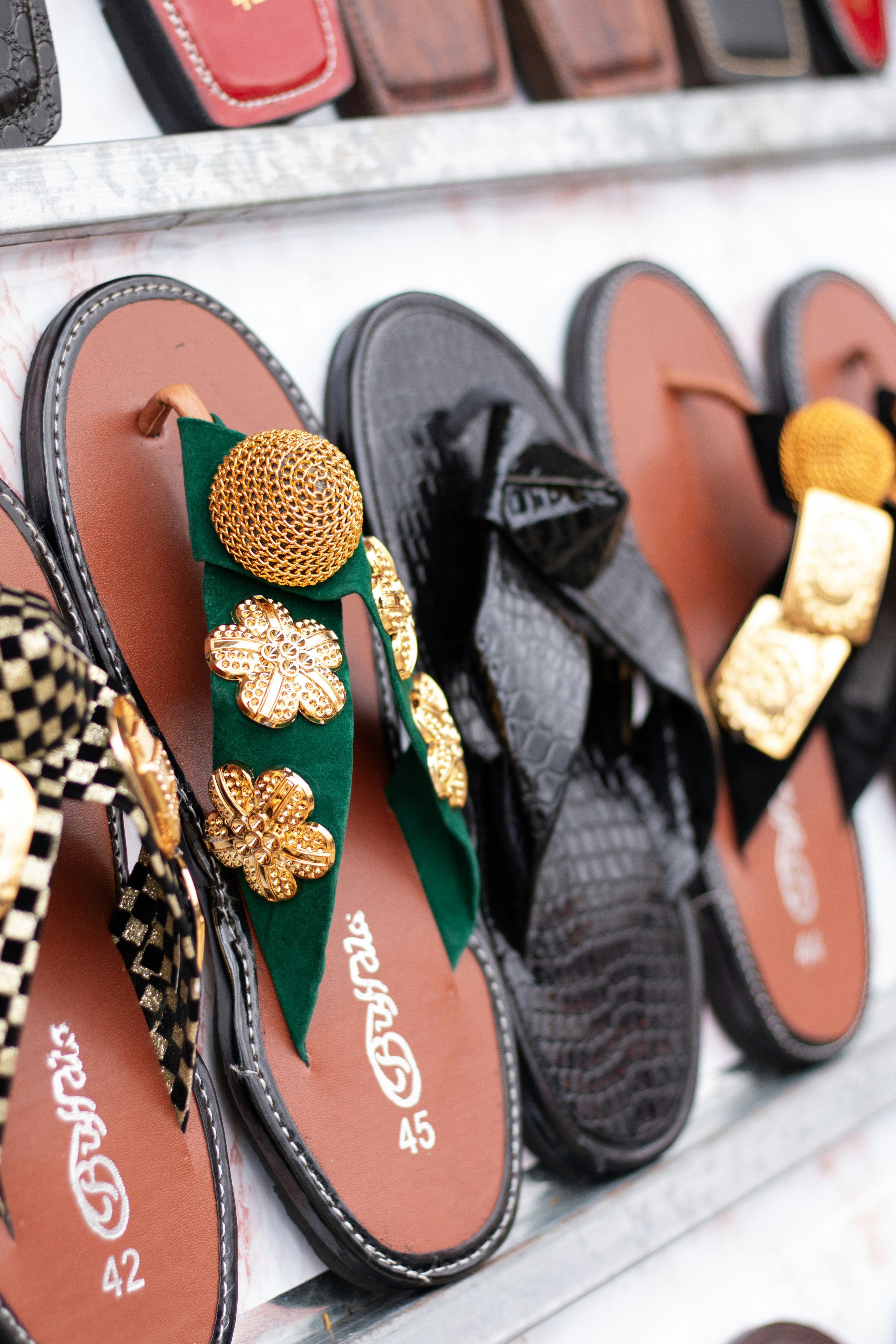 Row of decorative women's sandals displayed on a shelf.